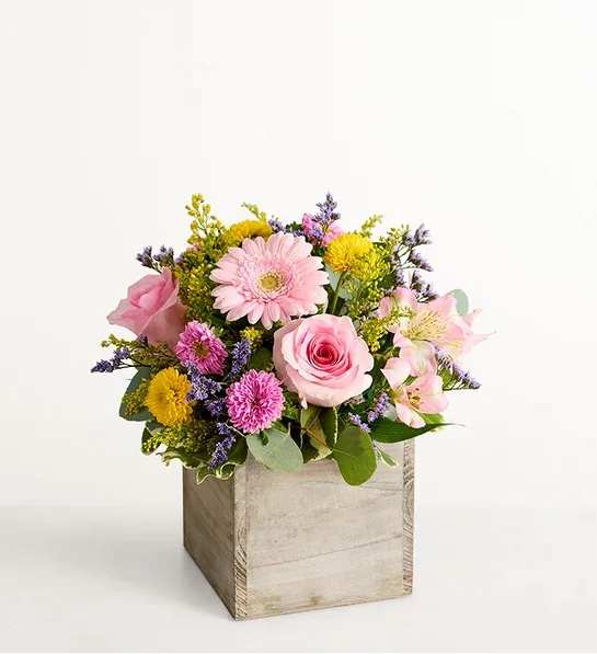 Spring Sentiment - Spring is a time to refresh and reach out. Our spring bouquet celebrates that sentiment. Pastel pink and yellow blooms are loosely gathered with lush greenery for style and texture. Designed in our rustic, gray-washed wooden cube, it’s a gift that delivers on your feelings in the most beautiful way.