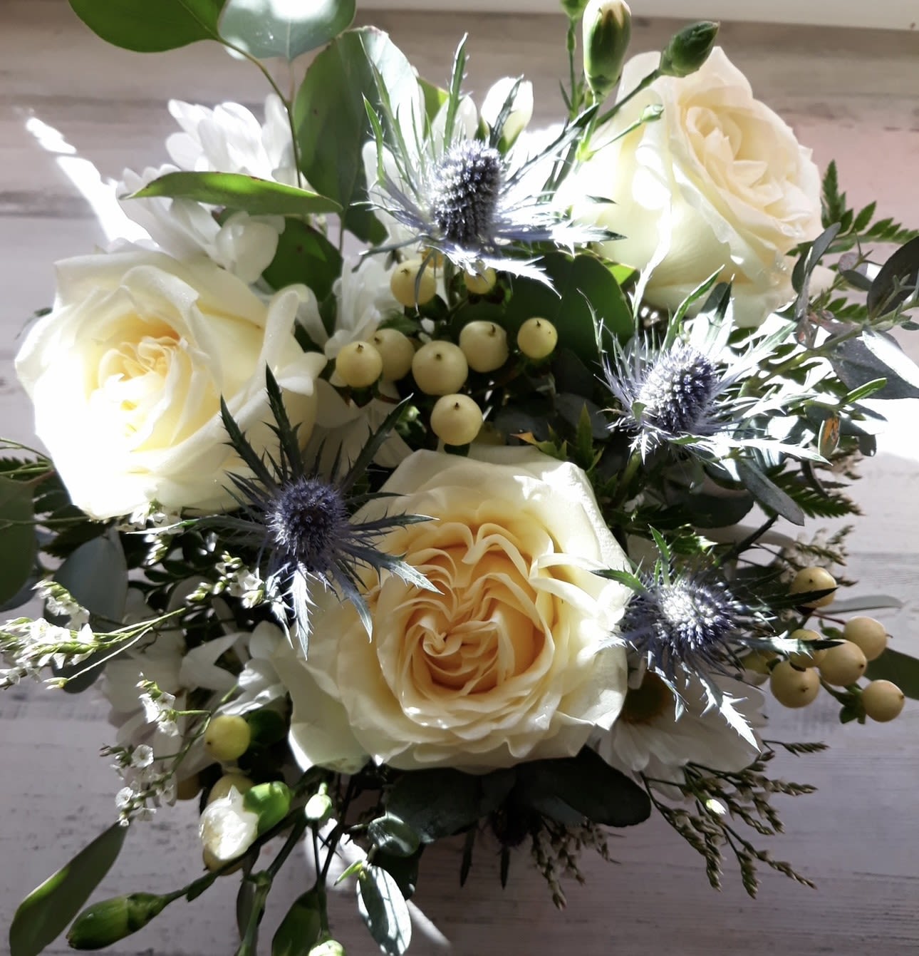 SEASIDE MEMORIES CUBE - A GLASS CUBE OF WHITE ROSES, BLUE SEA HOLLY , HYPERICUM BERRIES AND MIXED GREENS 