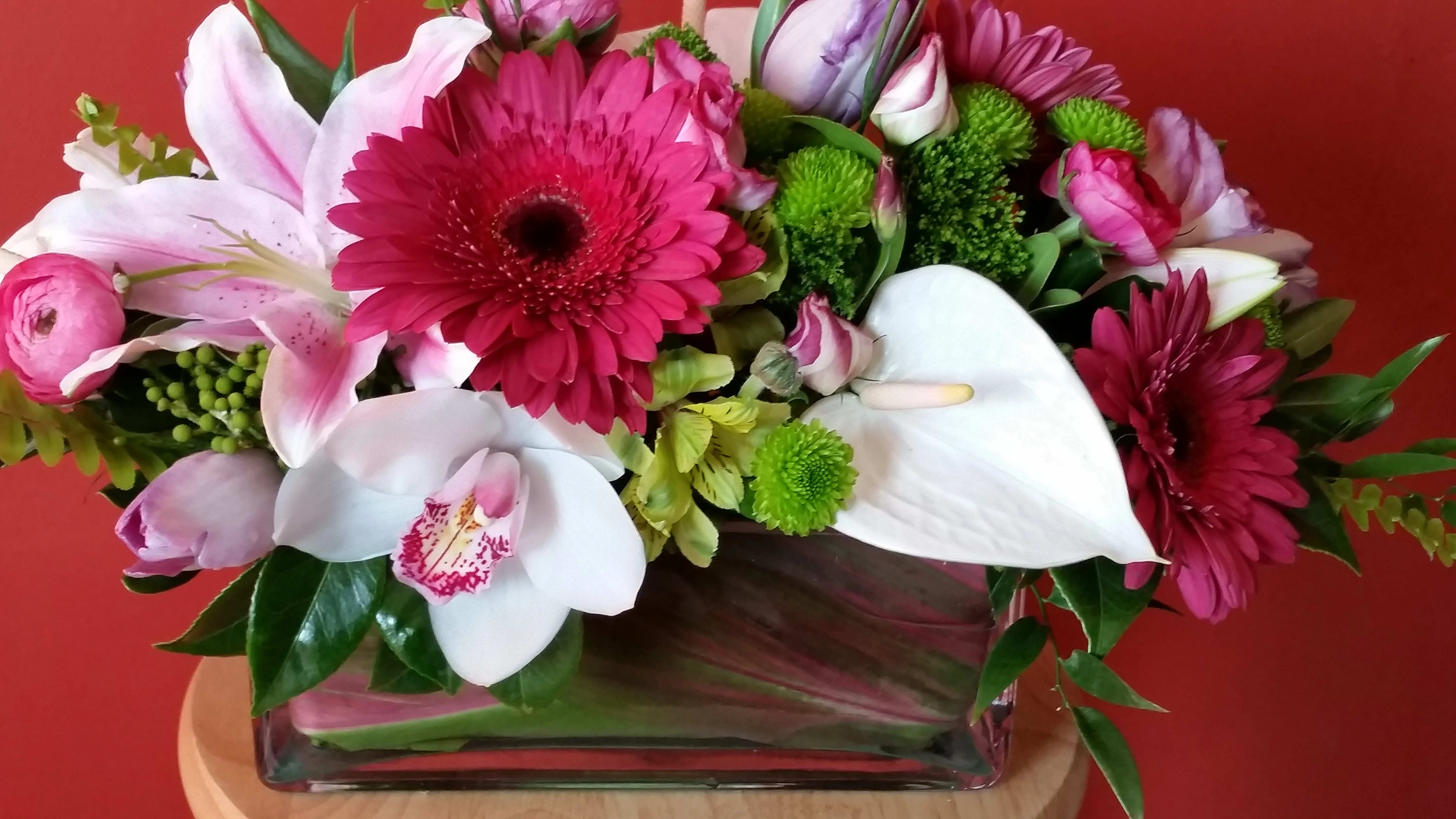 Raspberry Wishes - If you are looking for a centerpiece that is unlike the 'typical' mounded ball of flowers in a plastic bowl, consider our Raspberry Wishes arrangement.   We've taken pink Oriental lilies, tropical white anthurium, white cymbidium orchid and fuchsia Gerbera daisies and arranged them in a thick glass rectangular vase.  We line the vase with a beautiful ginger leaf and the finished product is just spectacular! 
