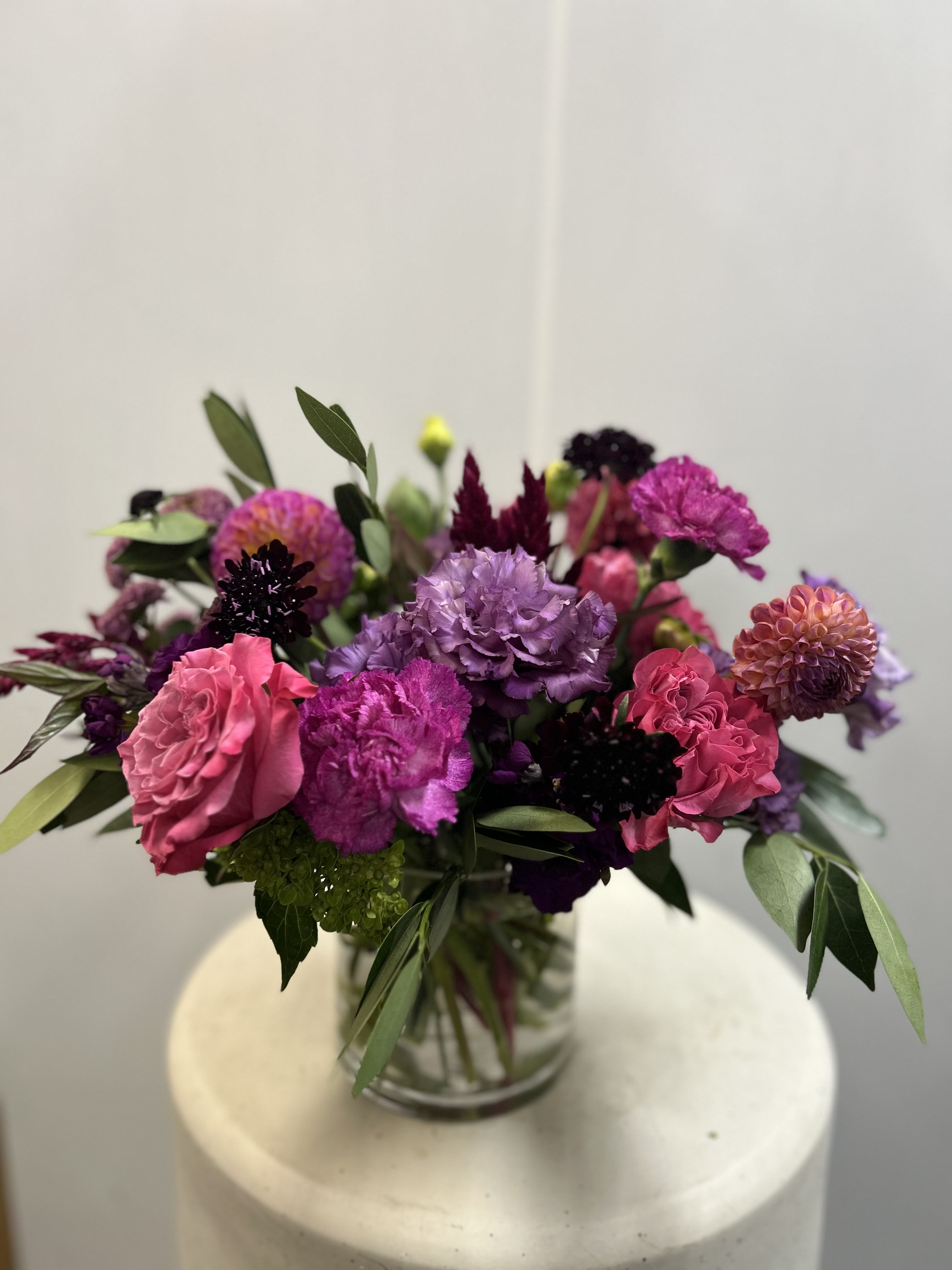 Dancing in the Dark - Beautiful arrangement created with rich jewel tones. Consists of roses, dahlias, lisianthus and other seasonal flowers. 