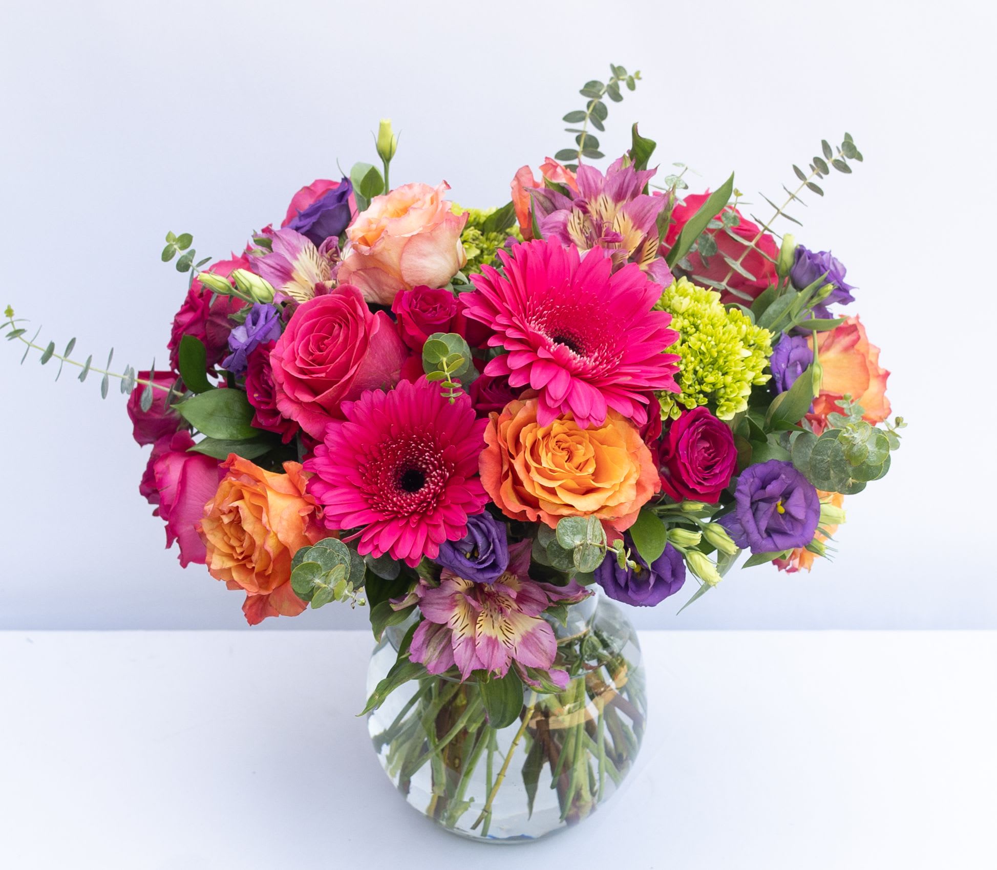 Mixed bouquet of pink, orange, and purple flowers in a glass vase