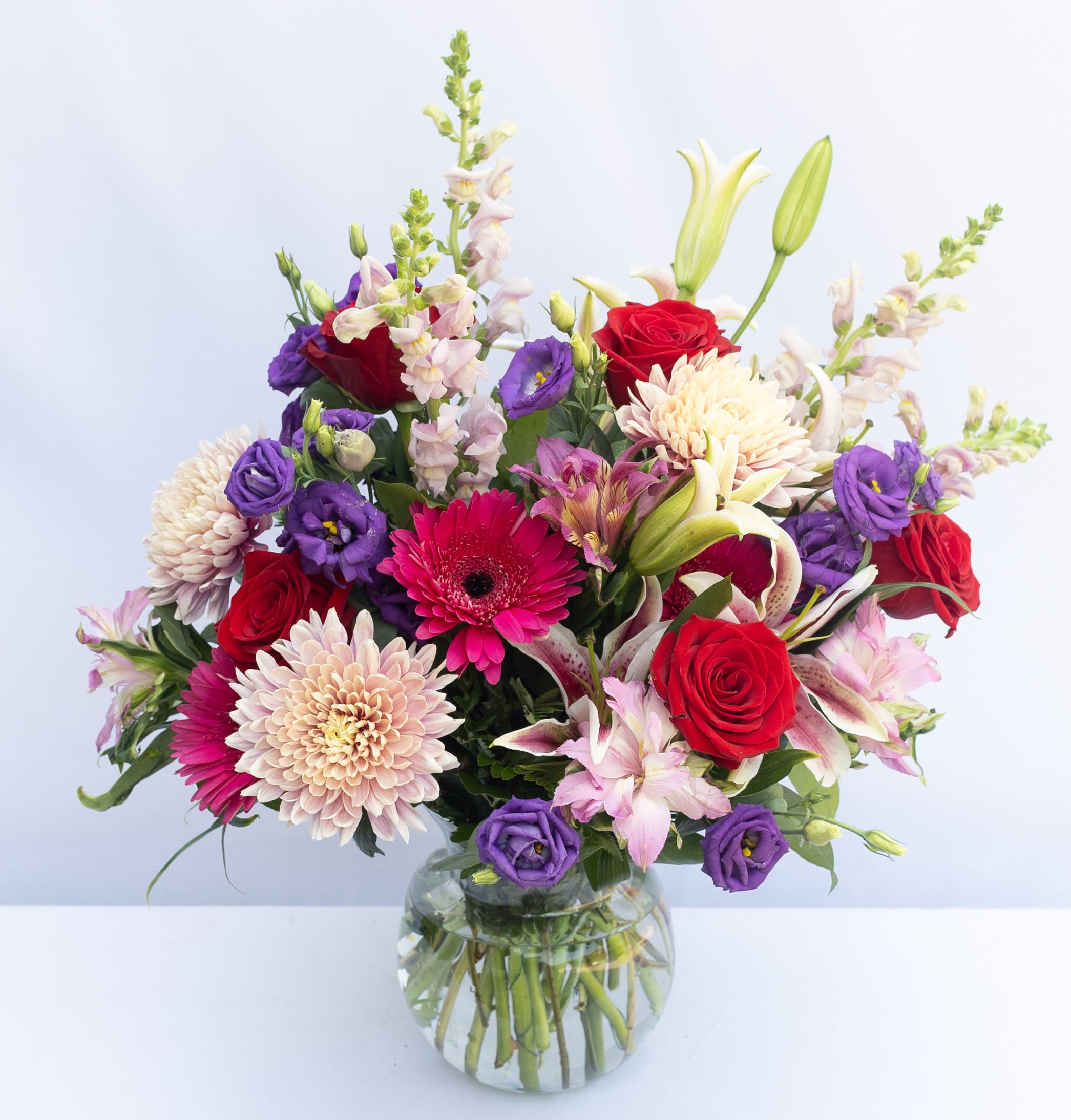 Mixed bouquet of red, purple, and pink flowers in a glass vase