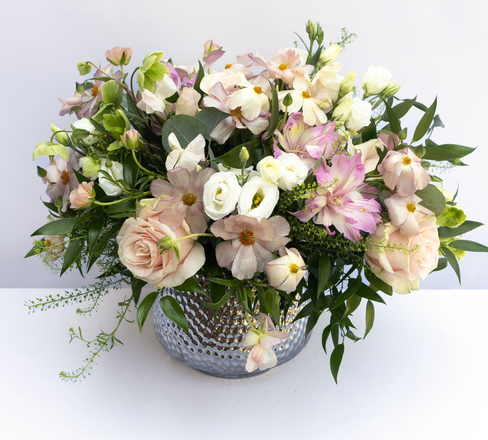 Blushing Pastel  - A soft mix of blush pink flowers arrangement in a silver hammered vase. Flowers may include light pink roses, pink ranunculus, Lisianthus and other seasonal blush flowers