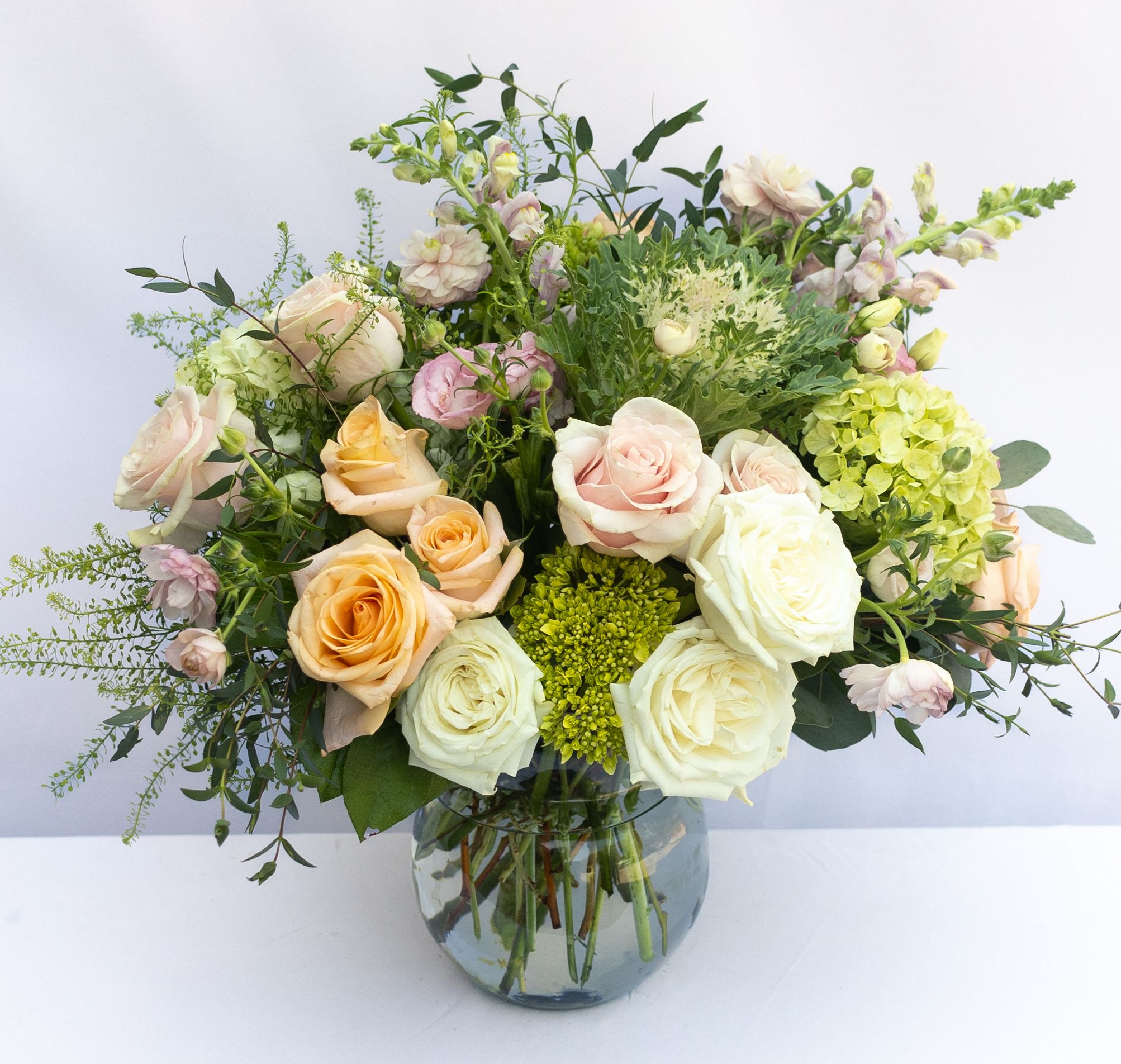 Mixed pastel roses and greenery in a glass vase