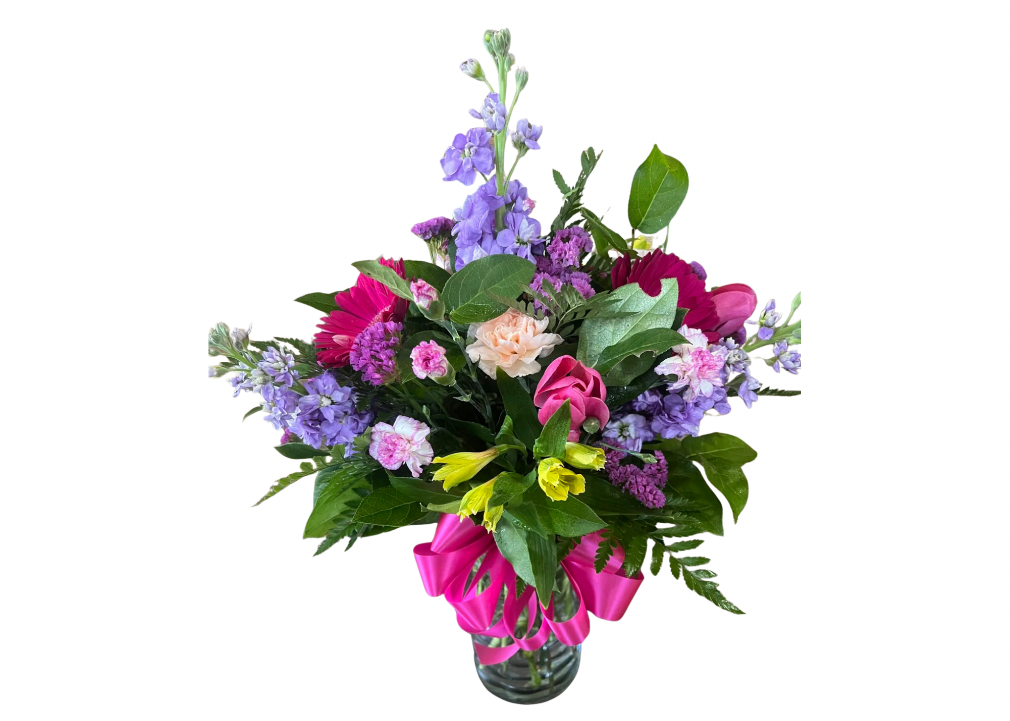 Mixed bouquet of pink, purple, yellow, and peach flowers in a clear glass vase with a bright pink ribbon bow