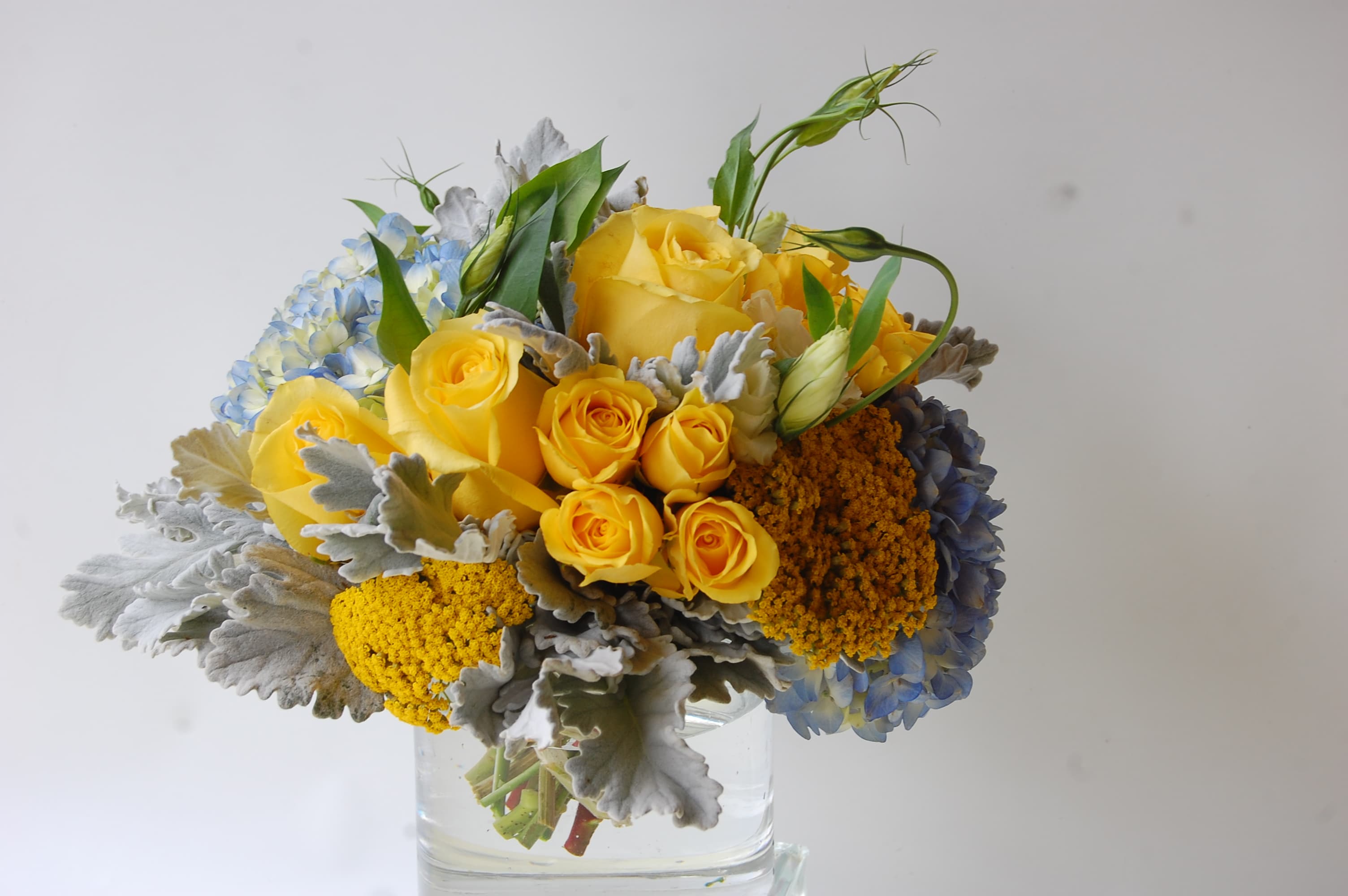 California Skies - This awe-inspiring arrangement calls to mind that glorious ray of light that boldly breaks through the clouds on a rainy day. Yellow roses and yarrow couple with lisianthus and blue hydrangea to recreate the blue skies of our hometown San Diego. What an unexpected breath of fresh air the sublime bouquet is. 