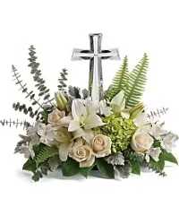 Life's Glory - A low, elongated sympathy arrangement that centers on a polished silver cross rising gently from a compact bed of blooms - the perfect floral tribute for a funeral, memorial service, or a quiet moment of remembrance at Easter. This flower arrangement for sympathy and "thinking of you" moments speaks with calm serenity: the cross provides a comforting religious focal point while the soft palette conveys grace and reverence.  Cream roses and soft white lilies sit alongside green hydrangea and delicate alstroemeria to create a tightly gathered, traditional composition. The cream, white, peach, and fresh green tones form a soothing visual rhythm that feels both respectful and uplifting. Sized as a low centerpiece, it works well on memorial tabletops or beside a loved one's resting place; it also serves as a meaningful way to say "I'm sorry" or "thank you" when words alone won't do. Care: keep in a cool location out of direct sun and refresh the water regularly to preserve the flowers' gentle beauty.