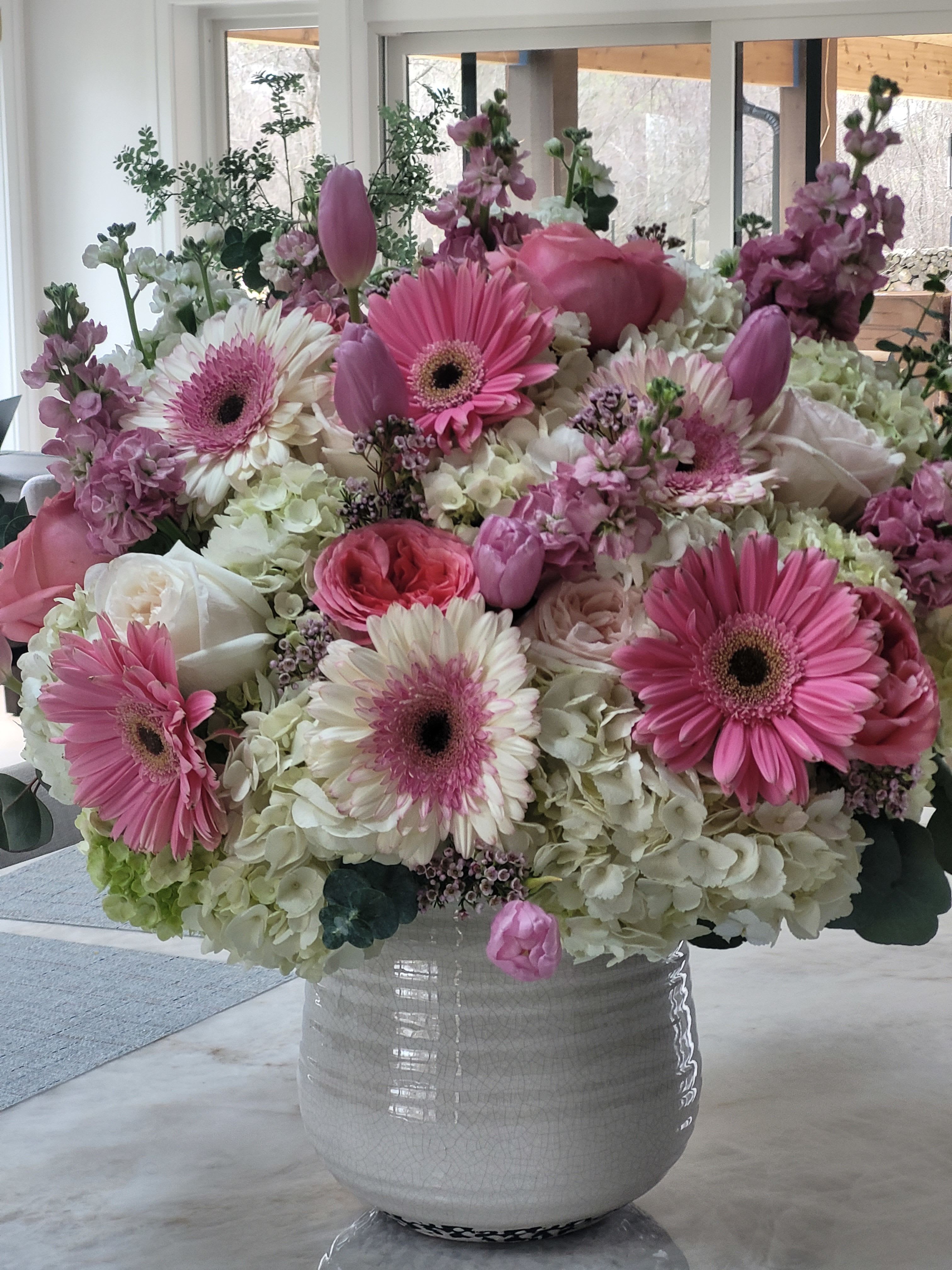 Petal Haus - A lush dome of soft pinks, lavenders and creamy whites-this flower arrangement is a joyful, springlike gift for birthdays, anniversaries, Mother's Day, or simply to make someone feel cherished. The rounded, feminine silhouette puts large pink and bi-color gerbera daisies front and center so the recipient sees cheerful blooms right away, while the pastel palette reads romantic without being fussy.  