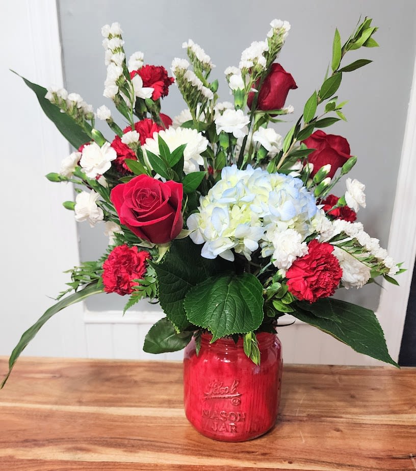 Americana - This arrangement has Beautiful red roses with amazing white flowers with a Fabulous hydrangea bloom in an americana mason jar vase!