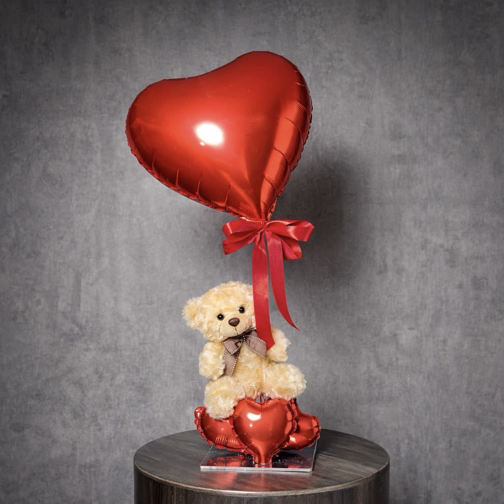 Sweetheart Lift - A sweet gift featuring a plush teddy bear with a red heart balloon on a stick and decorative heart balloons at the base. A charming romantic add-on that makes any flower delivery extra special.