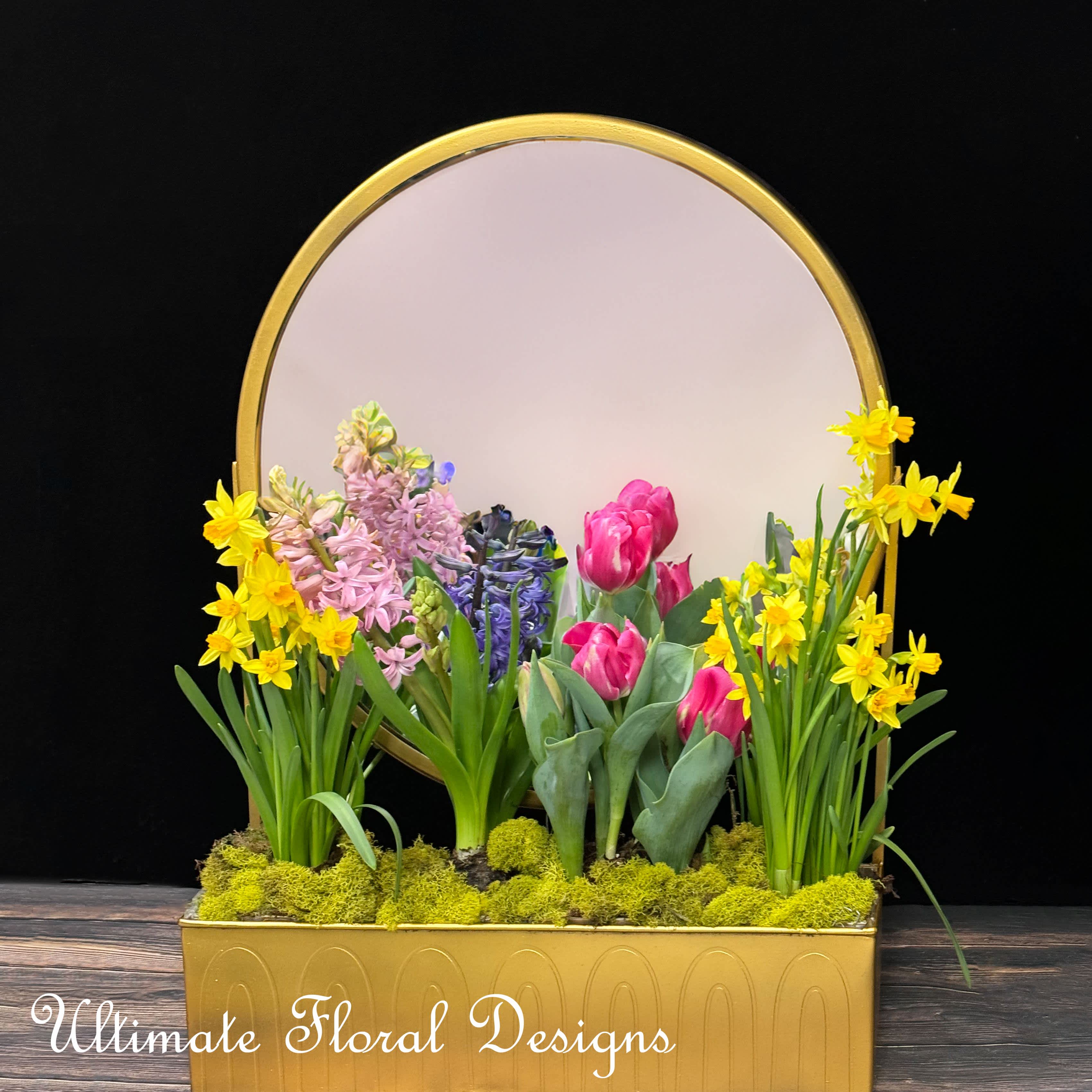 Spring Reflection Garden -  Name: "Spring Reflection Garden"  Bring the vibrant rebirth of spring indoors with the "Spring Reflection Garden", an arrangement where fresh tulips, daffodils, and hyacinth bloom in harmony, set against a mirror to double the joy and color. Perfect for brightening any space with the essence of a new beginning.