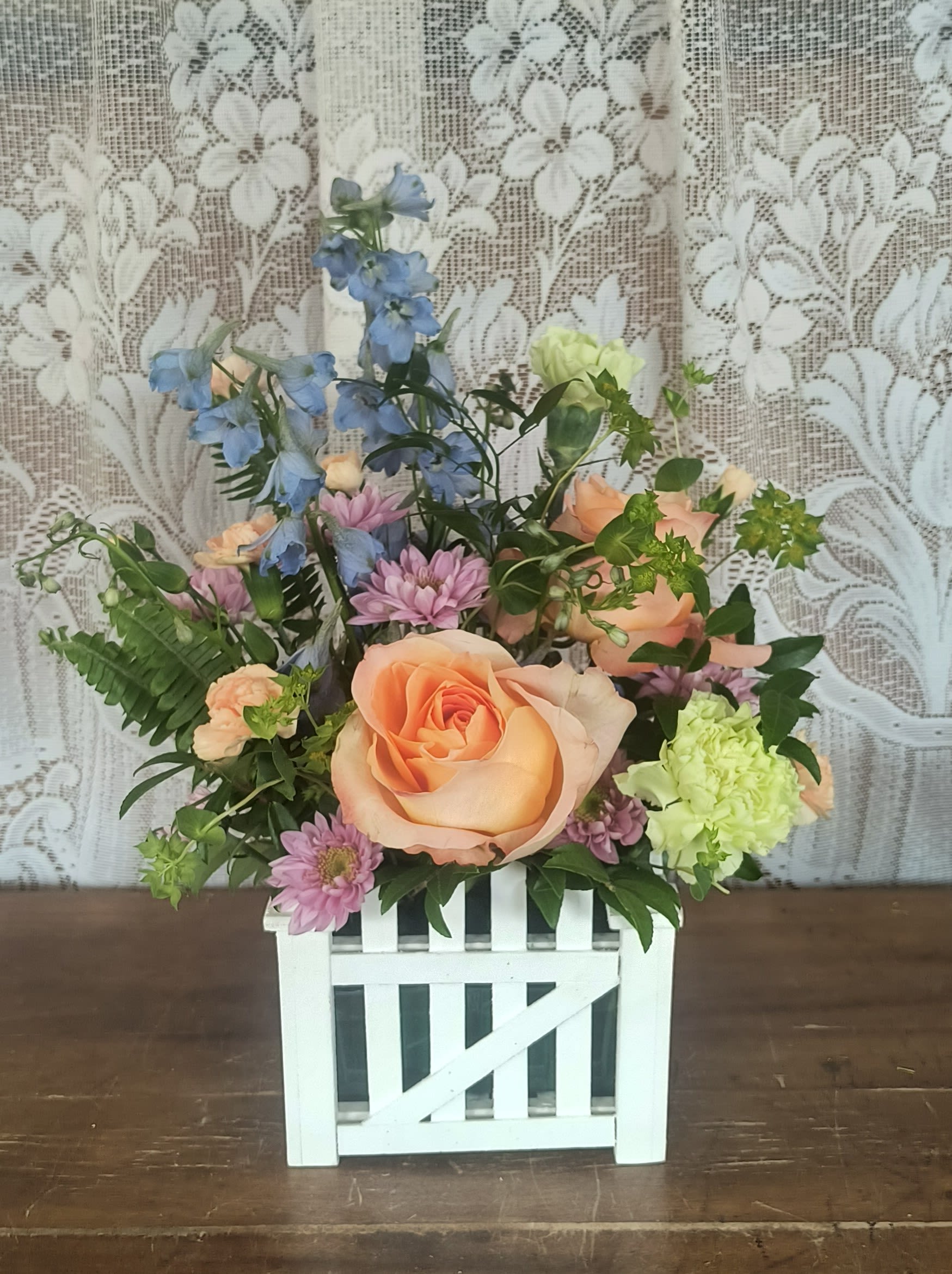 Garden's Gate - Spring colored blooms inside a white wooden picket fence planter.