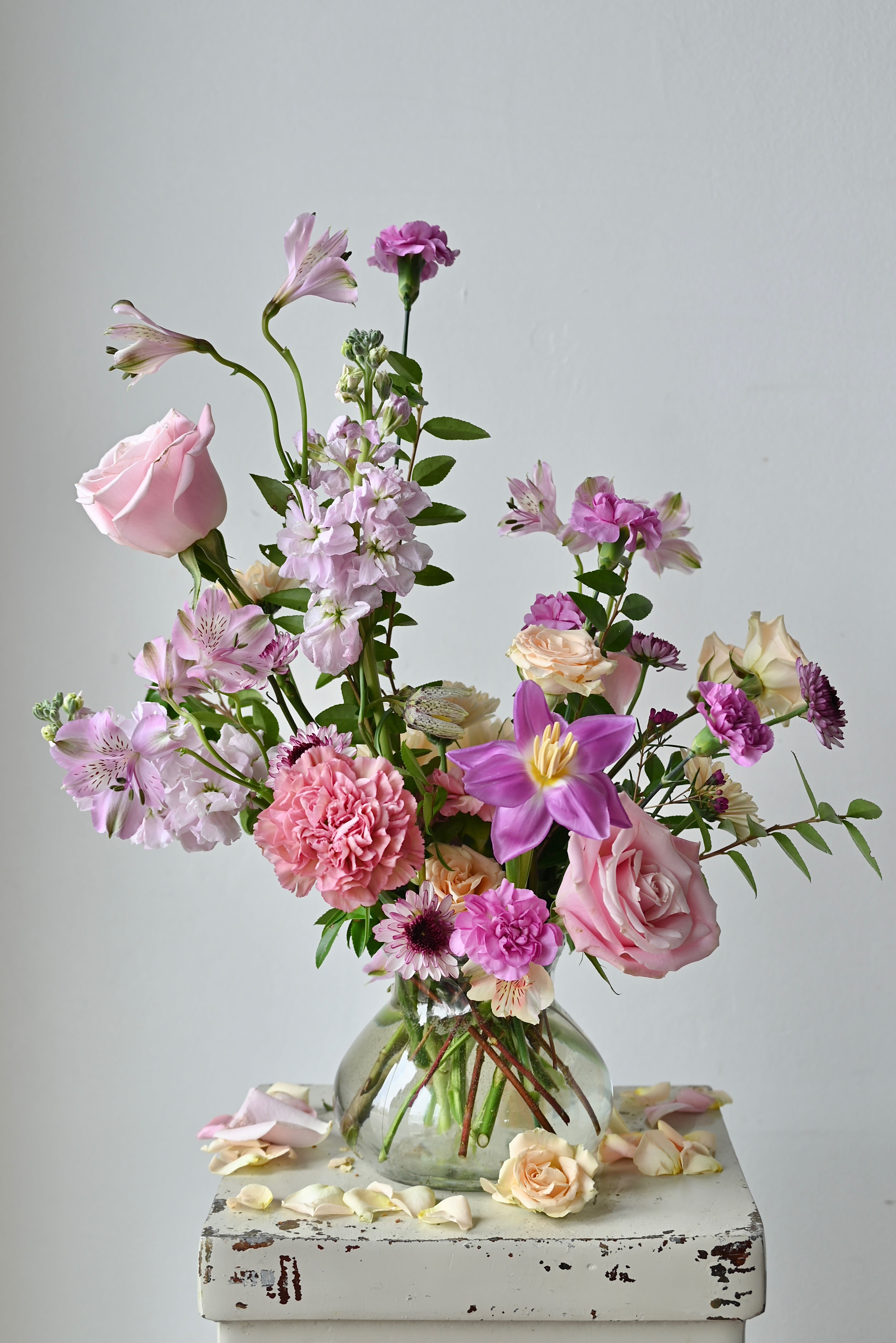 THE POSIE  - Meet your new favorite vase: the  Posie.  Featuring a seasonal mix of blooms, artfully designed in a fluted glass vase. Our team of expert designers will carefully choose the floral and color palette selection for a custom, unique and beautifully designed arrangement. Each piece is packaged with white tissue and wrapped in our black, textured logo ribbon.  *Please note that our color and floral palette changes from week to week. All substitutions will be of equal value.