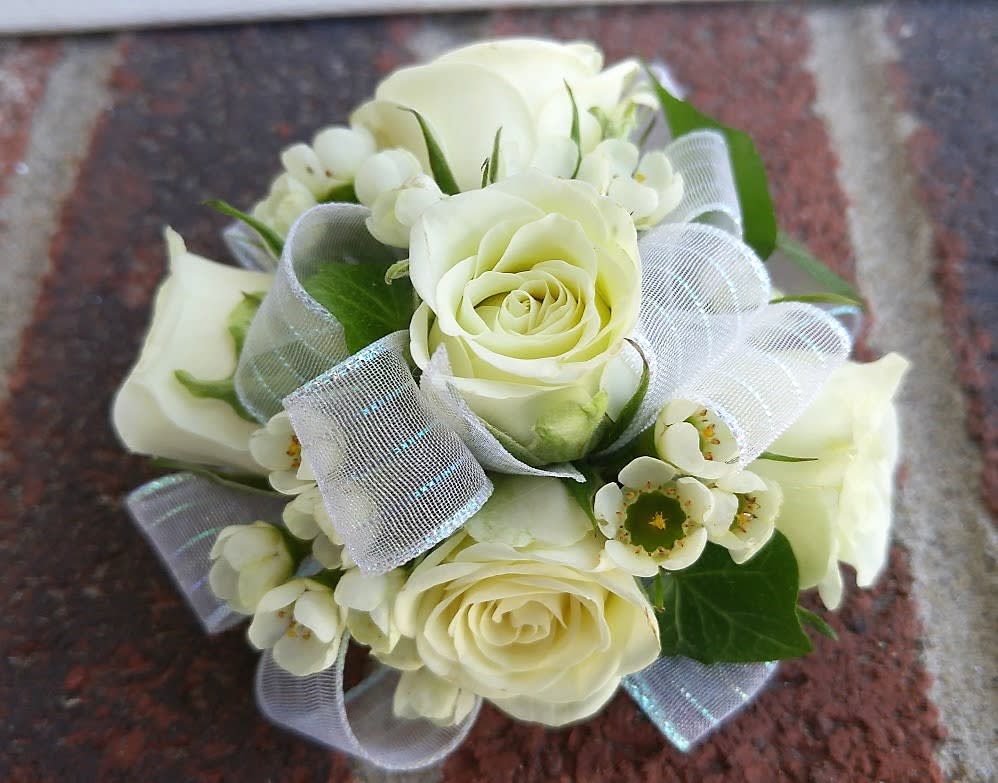 Traditional White Wristlet - Shown as Standard White spray roses, waxflower, ivy and white iridescent  ribbon come designed on a pearl wristlet. *Pick up only* *We custom design this arrangement and use the freshest flowers available the day of delivery. The arrangement in this picture is an example of the size and style and may not feature the exact product shown.*