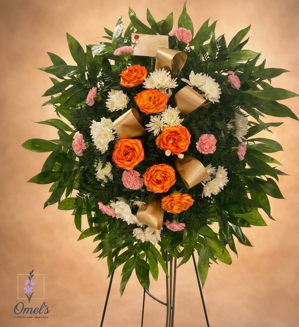 Standing spray of orange roses, white mums, and pink carnations with gold ribbons on an easel