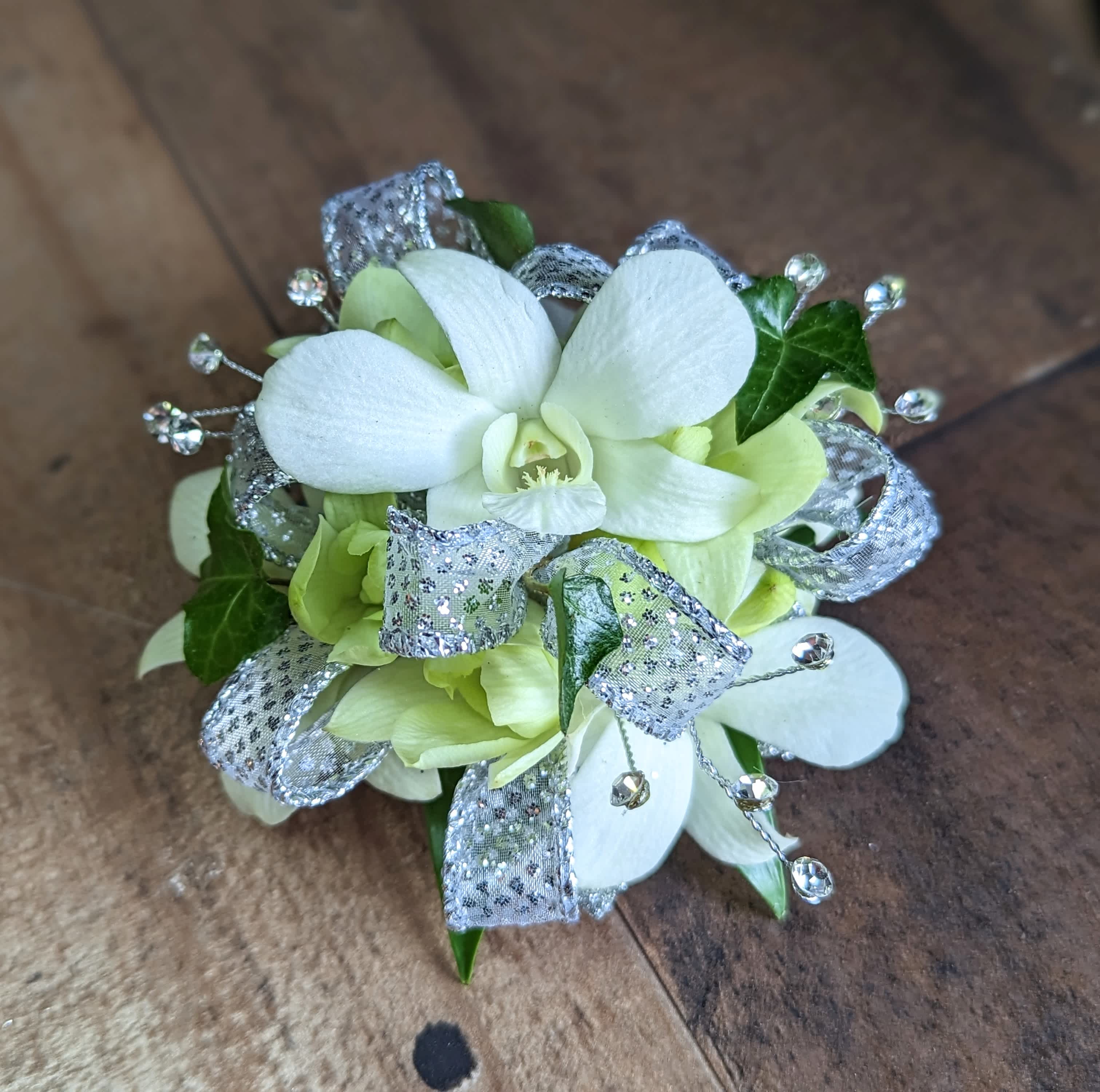 Silver &amp; White Dendrobium Corsage - Shown as Standard White dendrobium orchids, greens, gems and sparkle ribbon come arranged on a pearl wristlet. *We custom design this arrangement and use the freshest flowers available the day of delivery. The arrangement in this picture is an example of the size and style and may not feature the exact product shown.*