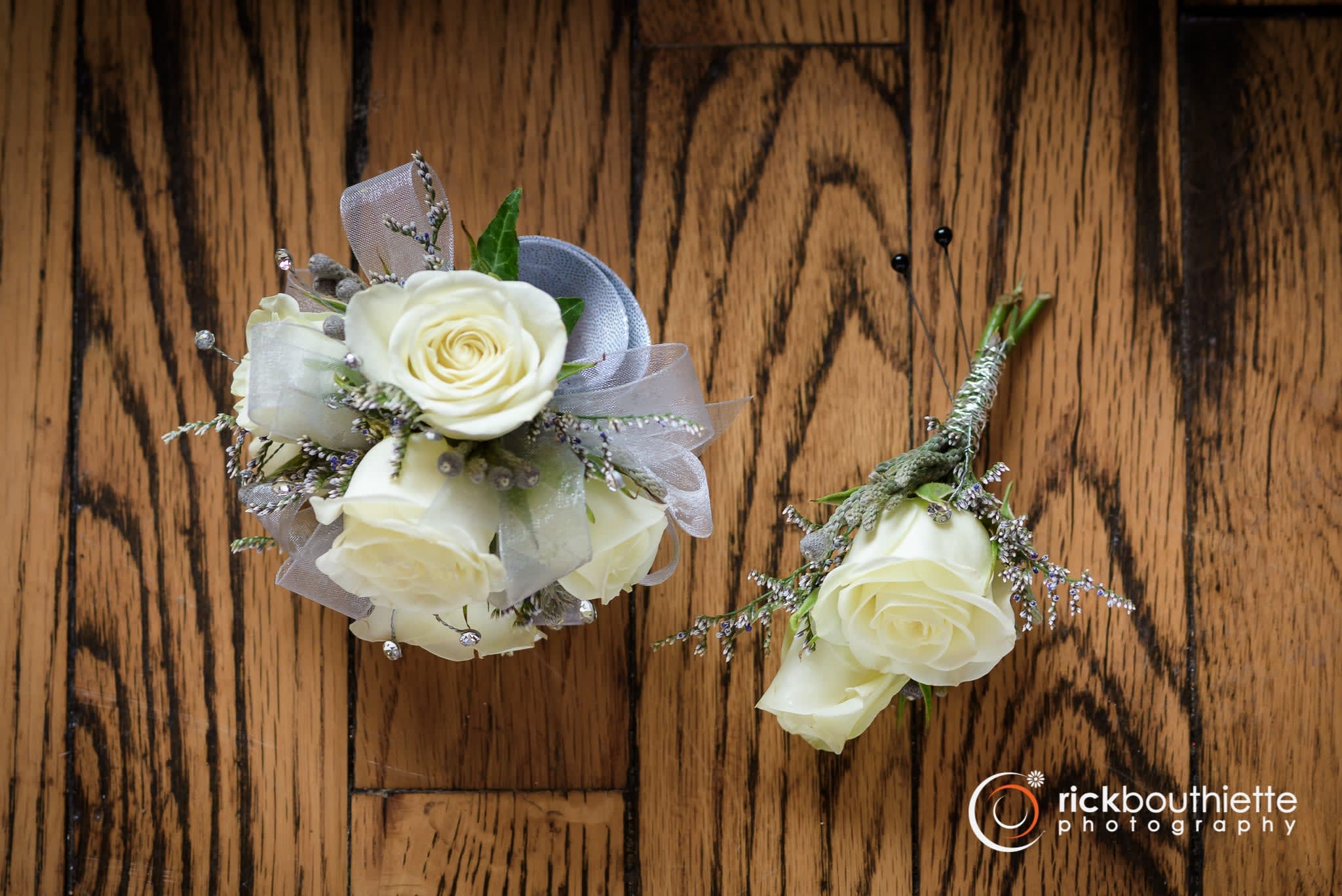 Silver &amp; White Corsage Combo - Shown as Standard White spray roses, caspia greens gems and silver ribbon come designed on a snap wristlet accompanied by a matching boutonniere.   **You can change your ribbon color in special instructions** *We custom design this arrangement and use the freshest flowers available the day of delivery. The arrangement in this picture is an example of the size and style and may not feature the exact product shown.*
