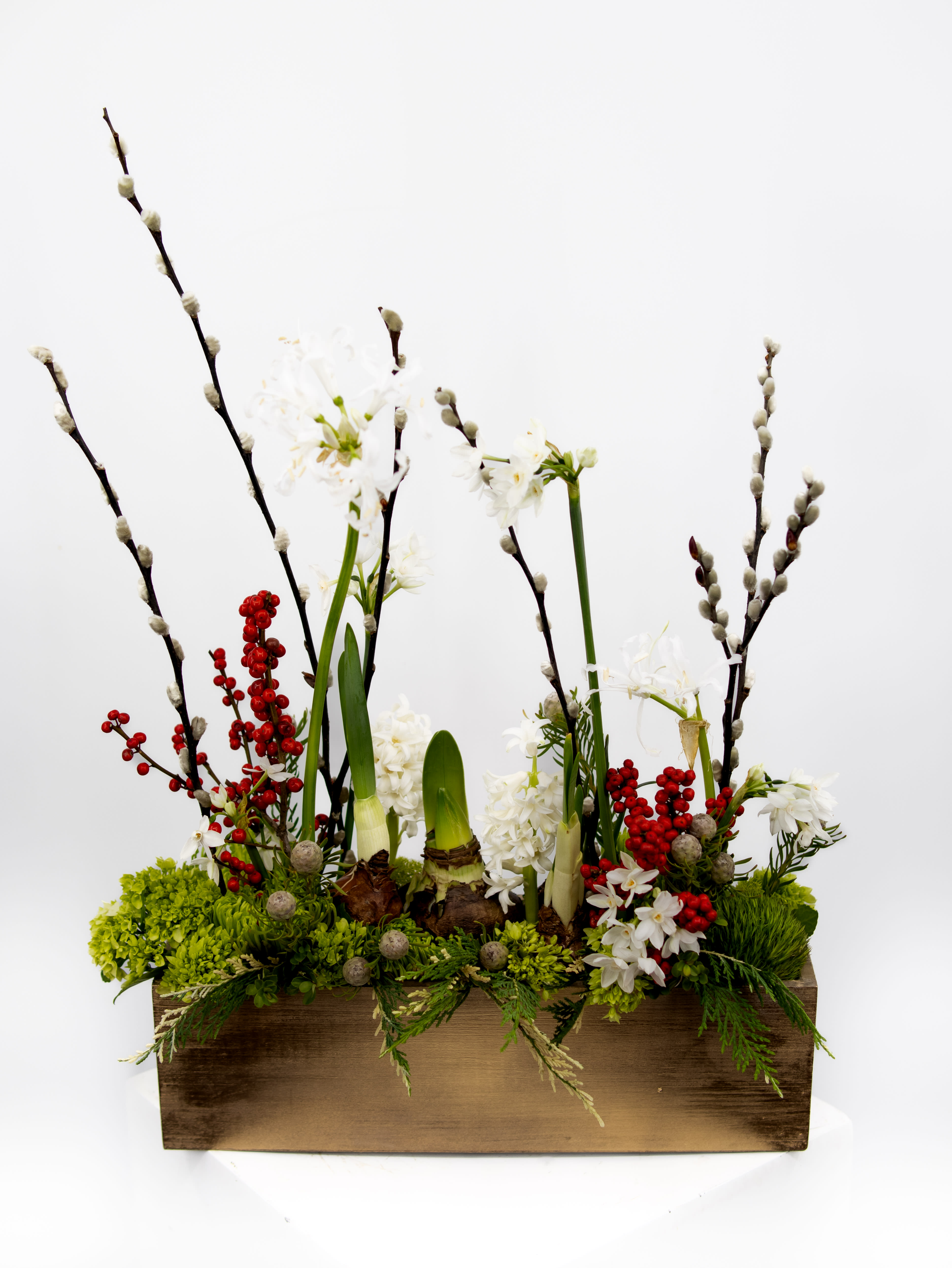 Cam -  A delightful floral arrangement meticulously crafted with an array of bulbed flowers nestled in a rustic wooden box. The charming ensemble showcases an assortment of bulb blooms, each bursting with life and color, creating a symphony of textures and shapes. Placed within the warm embrace of the wooden box, this arrangement effortlessly marries organic charm with a touch of rustic elegance, bringing the enchanting essence of a garden indoors.