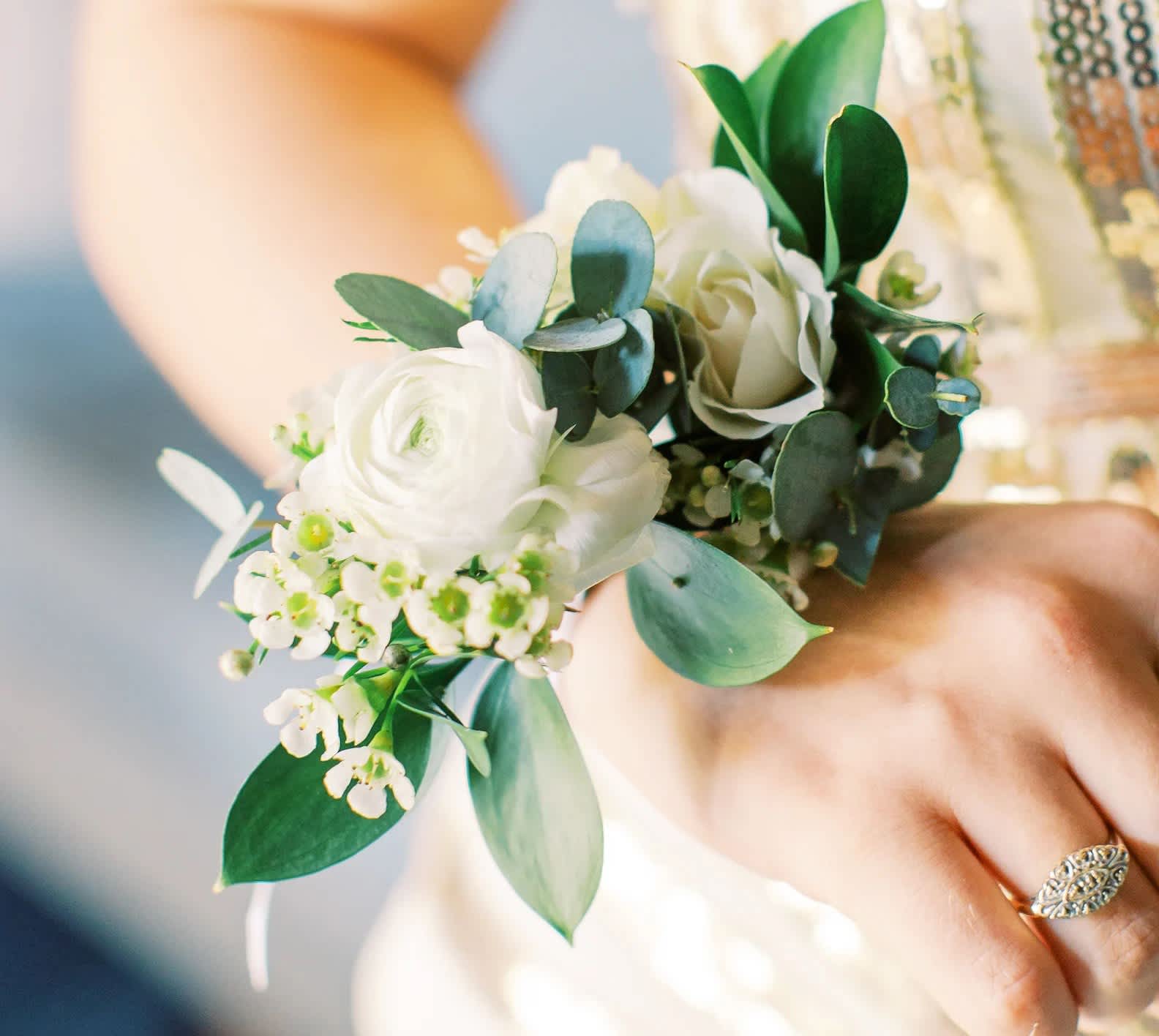 Wrist or Pin-on Corsage - Our corsages add a pop of sophistication and charm to any prom, wedding, or special event.  Please specify in the notes whether you would like a pin on or wrist corsage. Unless specified, all corsages will be made as a wrist corsage.  All corsages will be made with small white flowers and greenery. Although we cannot guarantee any specific colors, we are happy to work with color requests.  The deluxe corsage will be designed on a gold bracelet.  All corsages will be finished with natural double-faced white satin ribbon. Please remember to keep refrigerated before use.
