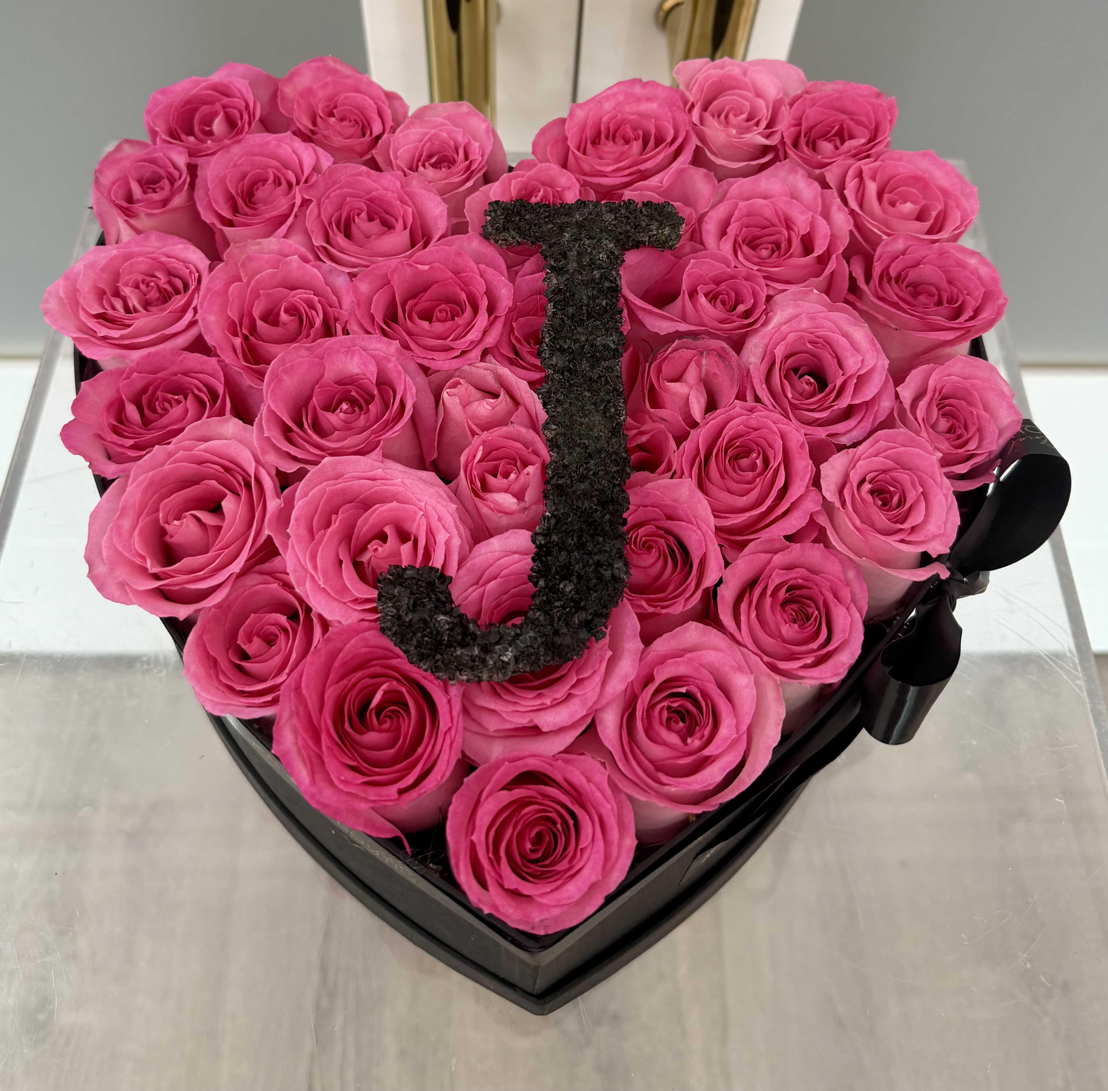 Initial Rose Heart Box - Make it personal, unforgettable, and effortlessly elegant. Our Initial Rose Heart Box features a stunning collection of premium, hand-selected roses arranged in a sleek heart-shaped box, finished with a custom initial designed with Baby's Breath flower for that signature touch.  Each bloom is carefully placed to create a full, lush look, while the bold initial centerpiece adds a meaningful and modern statement—perfect for celebrating someone special.  Details:     •    Fresh, high-quality roses      •    Elegant heart-shaped box design     •    Custom initial floral letter for a personalized touch     •    Perfect for birthdays, anniversaries, Valentine's, Mother’s Day, or romantic surprises   ** Roses color can be customize upon request (ex. Red, White, Blue, Yellow, Purple etc.)  *** Advance Notice Required: Custom floral initial arrangements require a minimum of 1 day advance notice to ensure availability and proper design.