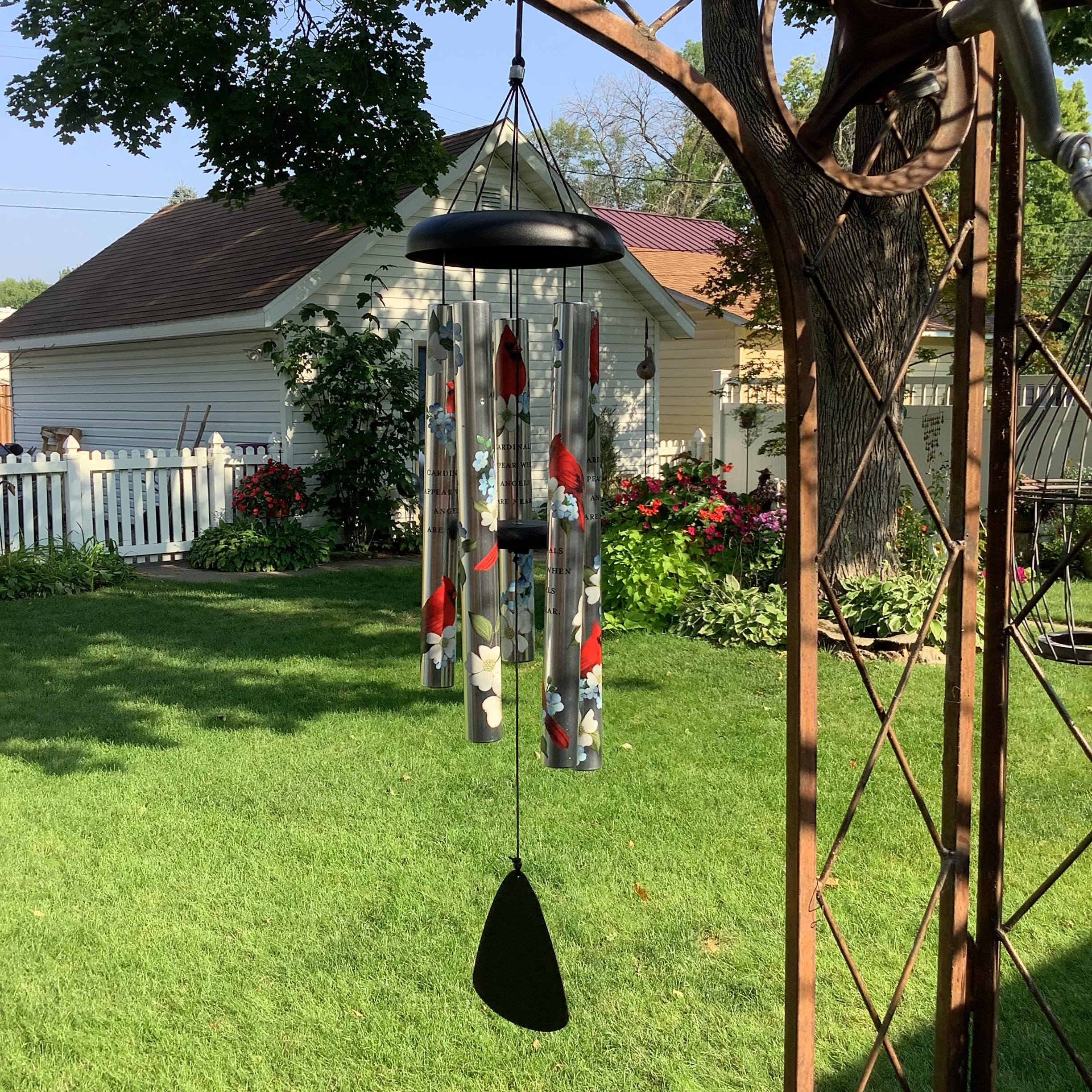 Hanging metal wind chime with painted cardinals in a garden