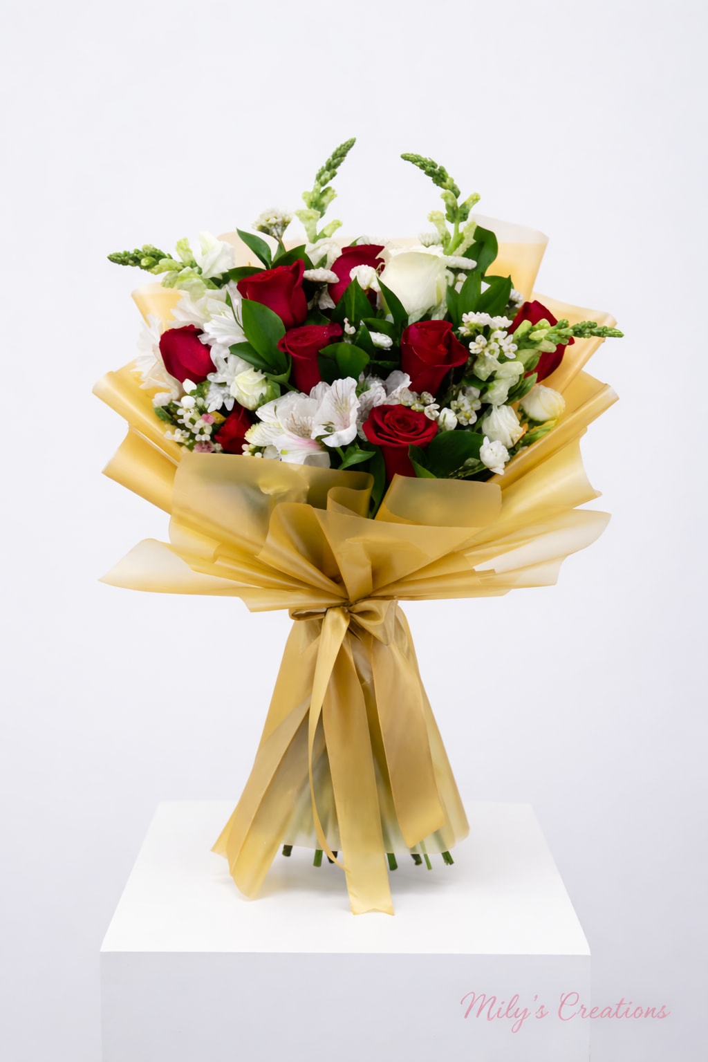 Hand-tied bouquet of red and white roses with white accent flowers wrapped in gold cellophane and ribbon.