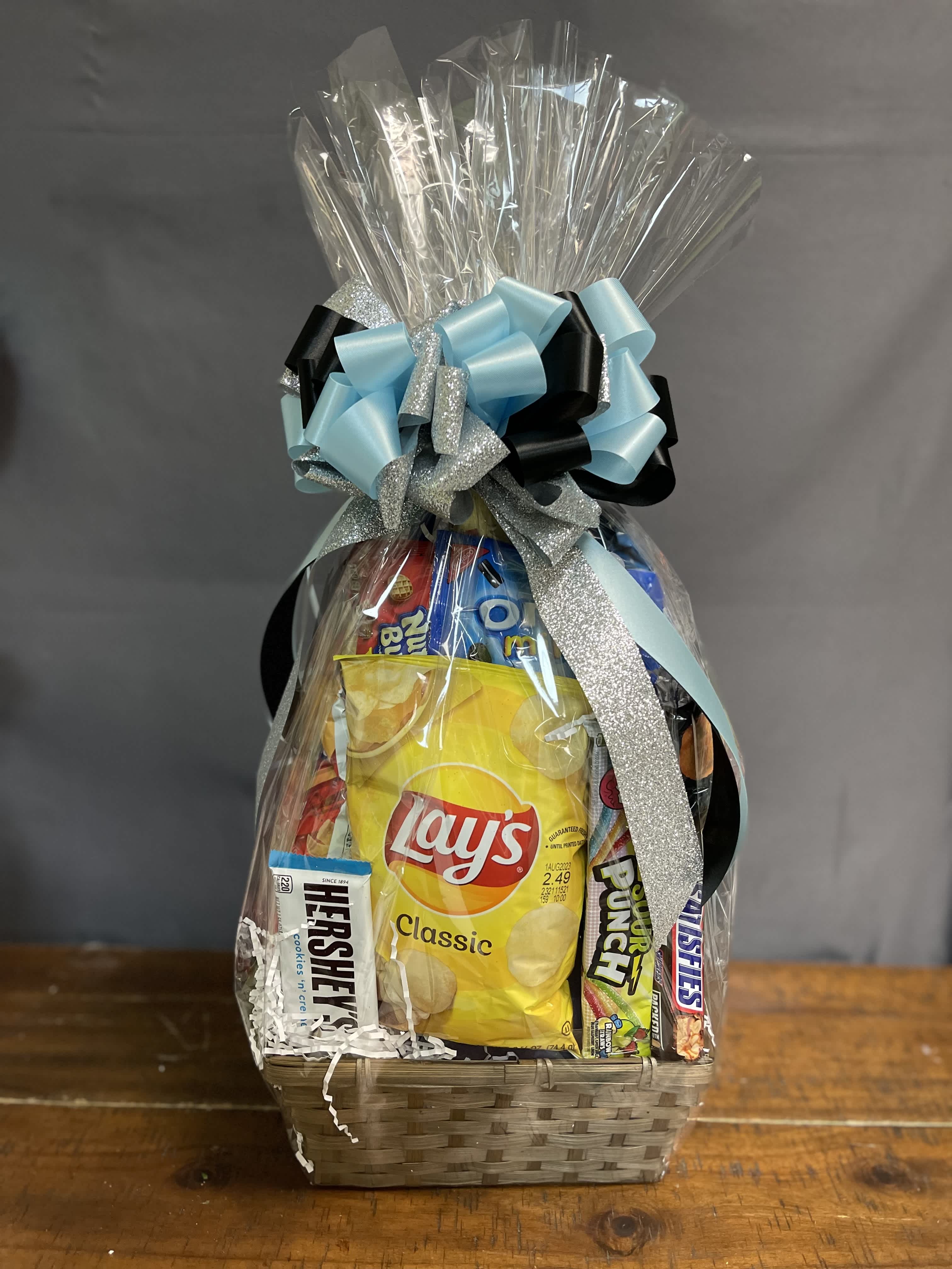 Gift basket wrapped in cellophane with assorted snacks and a large blue and silver bow