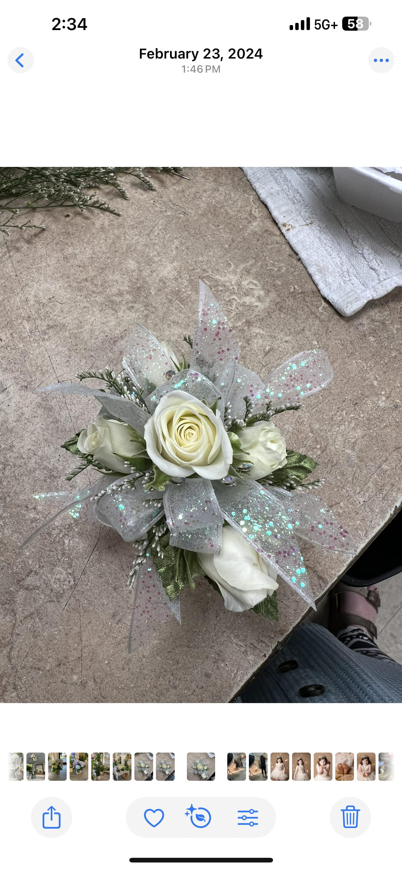 Small corsage of white roses with iridescent glitter ribbon on a work surface