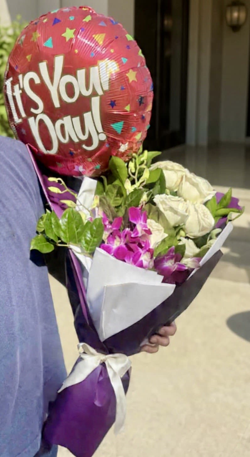 It's Your Day Balloon + White Roses &amp; Exotic Purple Orchids Hand Wrapped  Bouquet  - Say more than just "Happy Birthday" or "Happy Anniversary" with this vibrant, hand-wrapped celebration bouquet, designed to make their day truly special. Featuring a luxurious mix of exotic purple orchids and classy white premium roses, this arrangement is perfect for new beginnings, big wins, or just saying "You've got this." The stems are expertly tied and wrapped in elegant purple paper, finished with a crisp white ribbon. It even includes a festive "It's Your Day!" balloon to complete the gift!  Features: *   Hand-tied bouquet featuring white roses and purple orchids. *   Elegantly wrapped in purple paper with a white ribbon finish. *   Includes a festive "It's Your Day!" Mylar balloon. *   Ideal for birthdays, celebrations, or any special occasion.