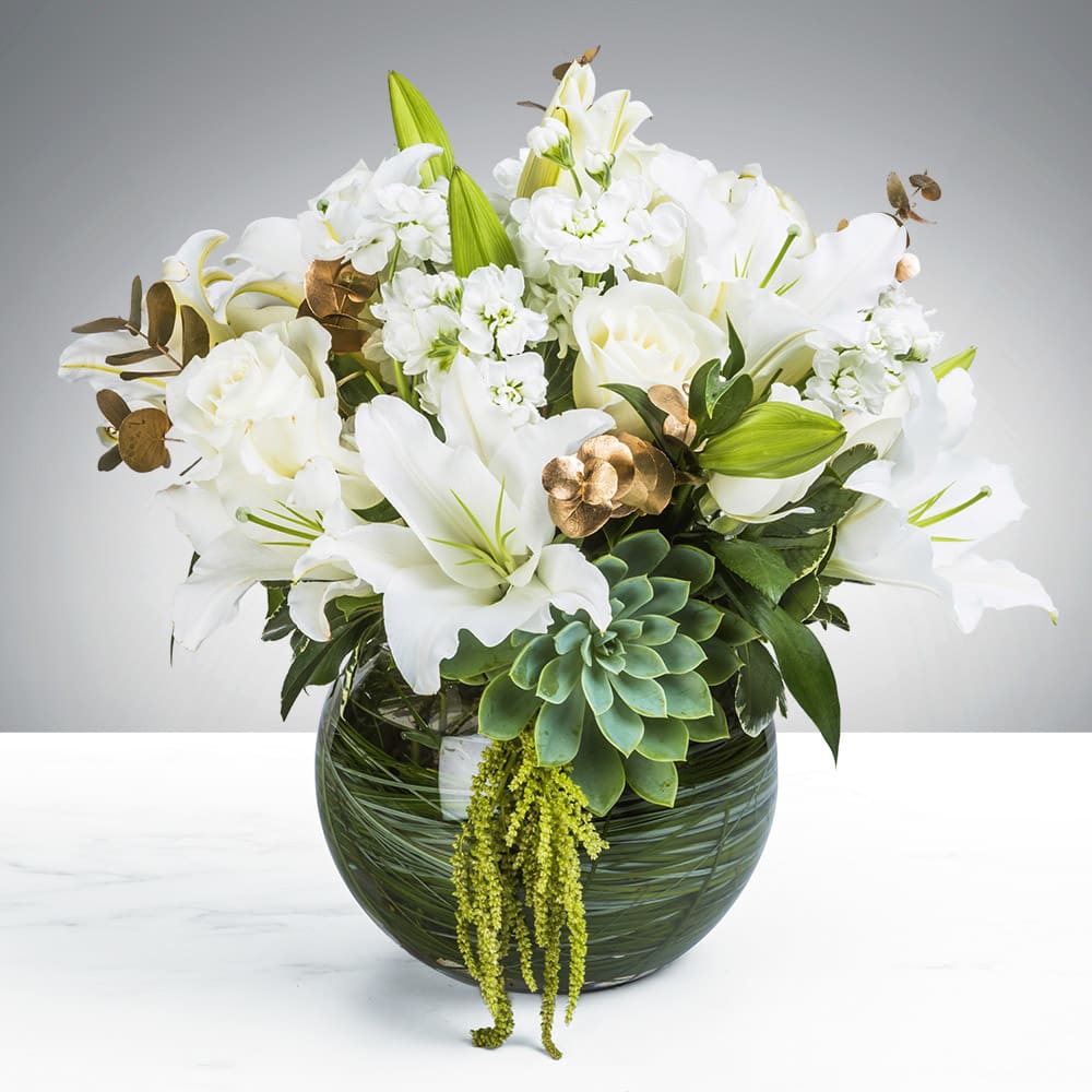 White lilies and roses with succulents in a round green glass vase