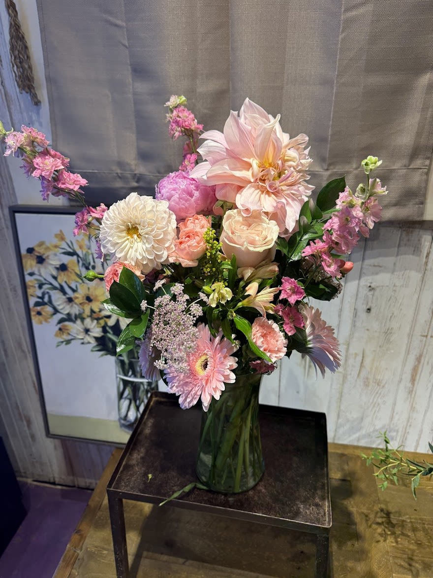 Pastel pink and white mixed flower arrangement with dahlias, roses, and gerberas in a clear glass vase