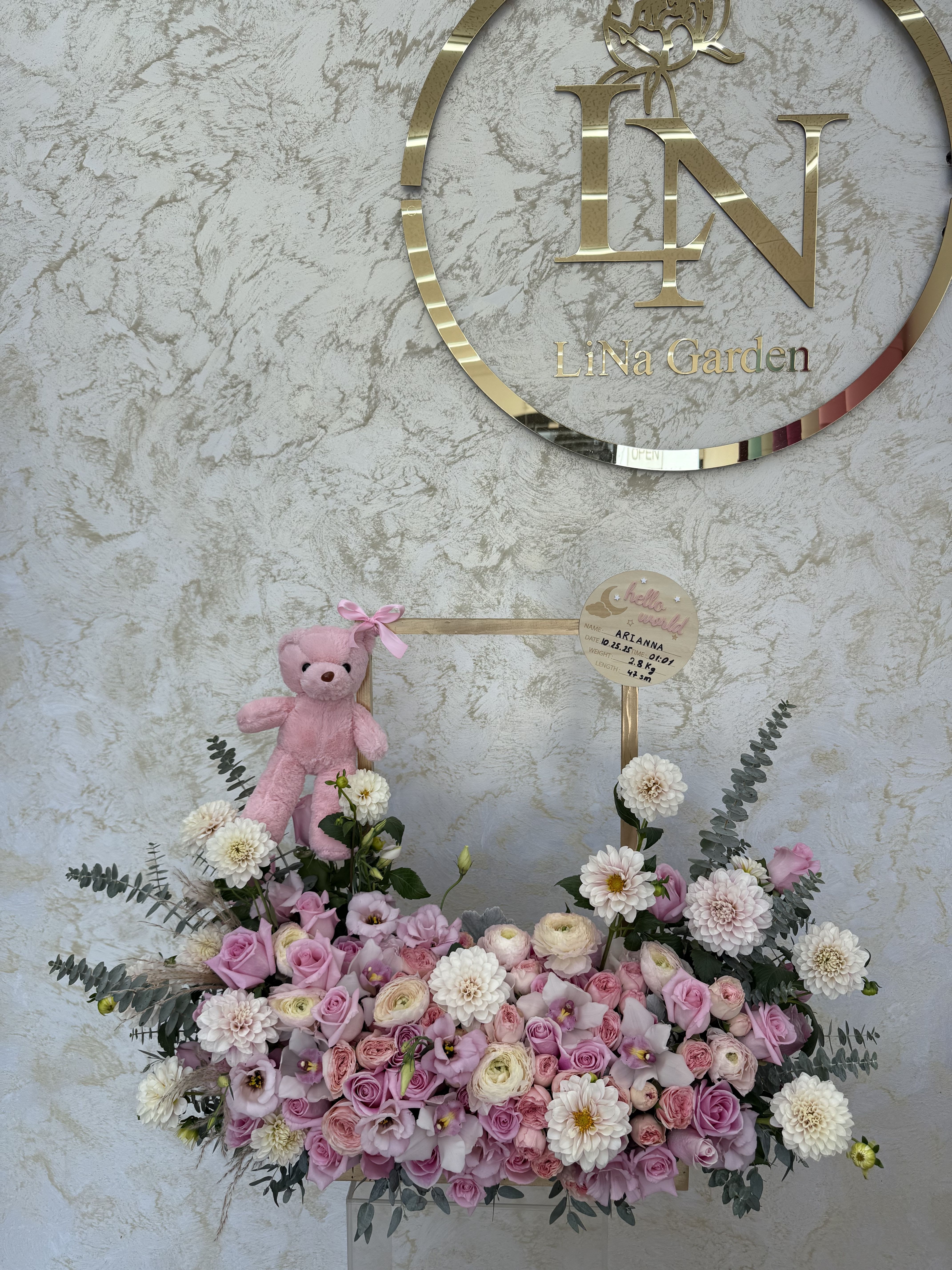 Pink and white rose arrangement in a low box with mums, lisianthus, eucalyptus, and a small pink teddy bear on a handle.