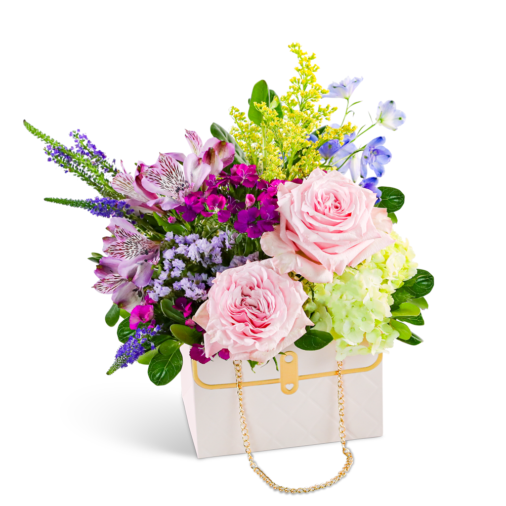 Petal Prelude Clutch - "Our Petal Prelude Clutch design showcases a stunning array of Roses, Hydrangea, Delphinium, Veronica, Alstroemeria, and premium foliage, creating a charming wildflower look. Perfect for those who appreciate a touch of whimsy and nature-inspired beauty, this design is elegantly arranged in a fashionable flower box purse. Add a touch of floral flair to their day with this unique and enchanting floral design. As a trusted local florist, we take pride in every order, offering hand-crafted flower designs delivered directly to the recipient. Our flower shop is committed to providing the highest quality, freshest flowers, and ensuring timely delivery for every arrangement."