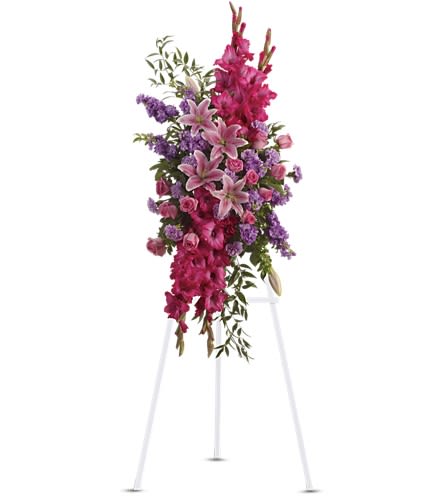 Tall pink and purple standing spray with lilies and roses on a white easel