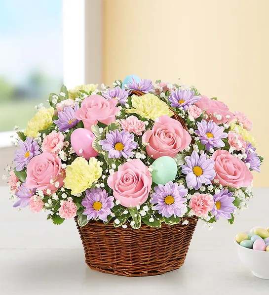 Pastel basket arrangement with pink roses, lavender daisies, carnations and decorative Easter eggs.