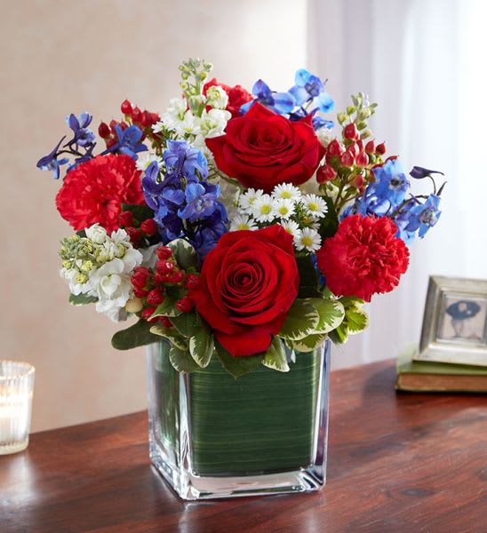 Red, white, and blue mixed flower arrangement in a square glass vase