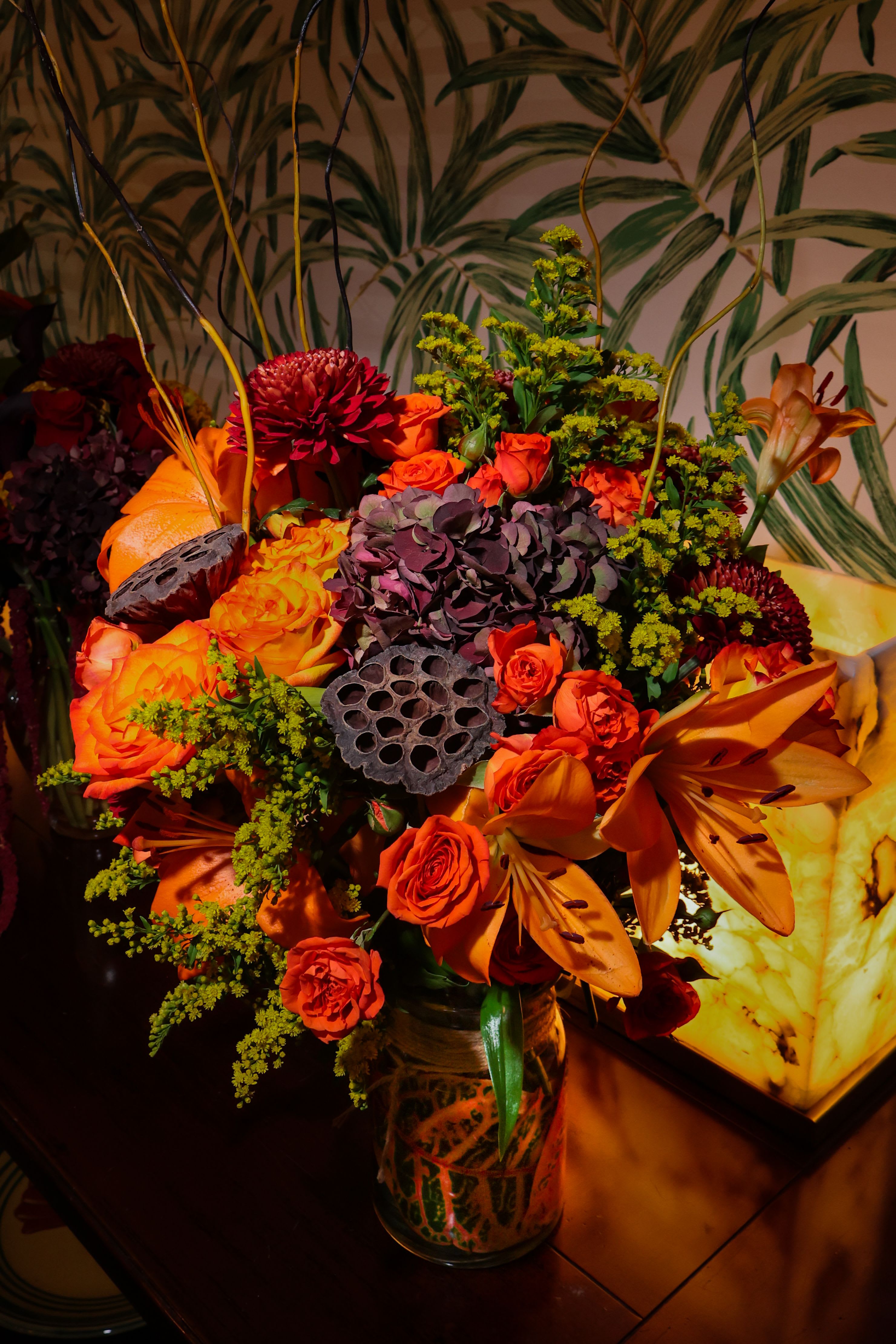 Autumn Bounty - A Large busting array of Autumn colors, including Roses, Spray Roses, Hydrangeas, Mums, Lotus pods, Lillys, Solidago, and Curly willow branches. Bound to Impress