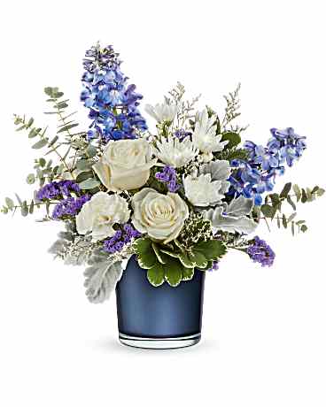 White roses and mums with blue delphinium and purple accents in a blue glass vase