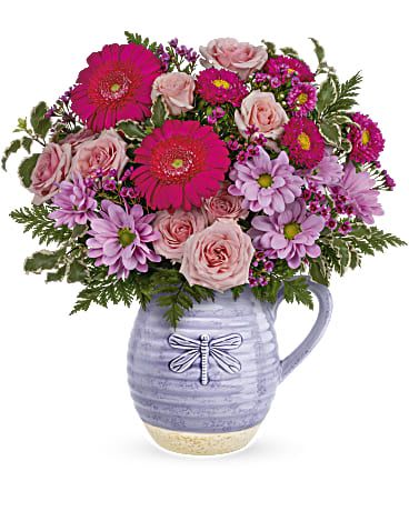 Pour On The Lavender Bouquet  - Lovely in lavender! With its beautiful artisanal glaze and whimsical dragonfly, this sweet ceramic pitcher--that's also food-safe makes the perfect presentation for a bright pink bouquet. This bouquet features pink spray roses, miniature hot pink gerberas, hot pink matsumoto asters, lavender daisy spray chrysanthemums, lavender waxflower, pitta negra and leatherleaf fern. Delivered in a Whimsical Dragonfly pitcher.   Approximately 15" W x 15 1/2" H