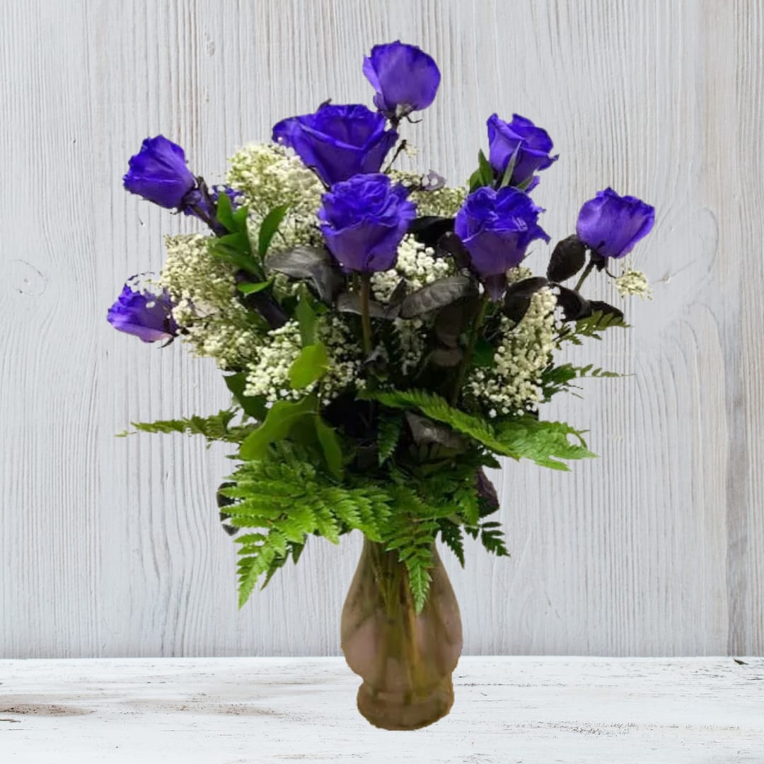 Arrangement of vivid purple roses with white filler flowers in a brown glass vase