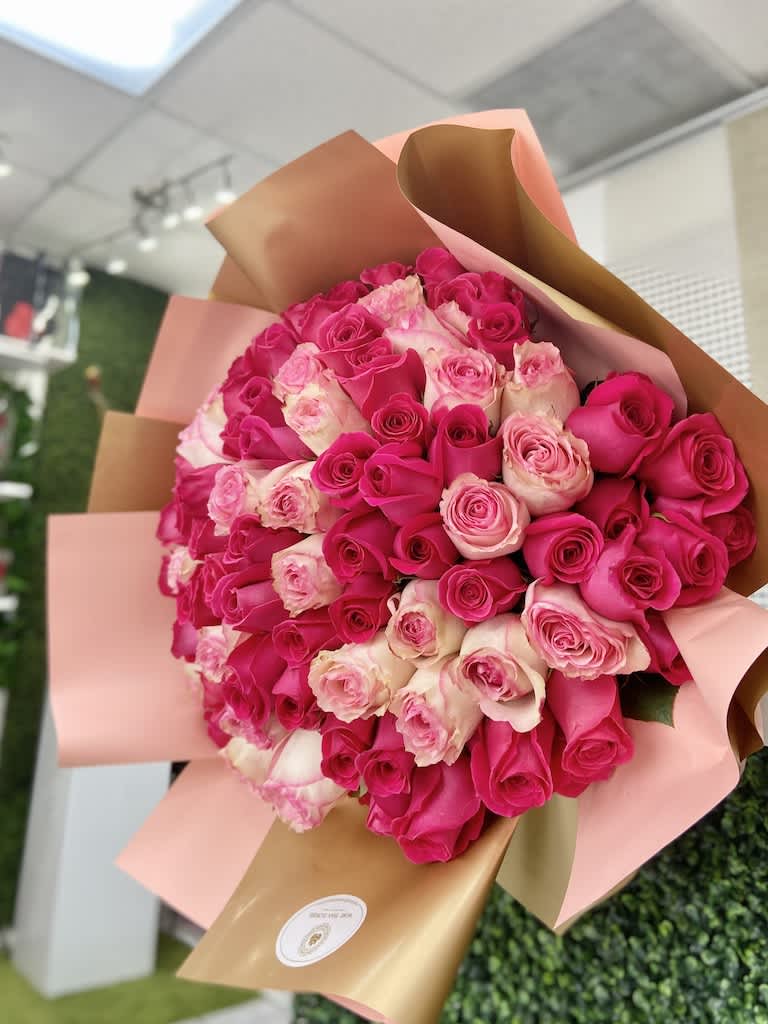 Large hand-tied bouquet of hot pink and light pink roses wrapped in blush and gold paper