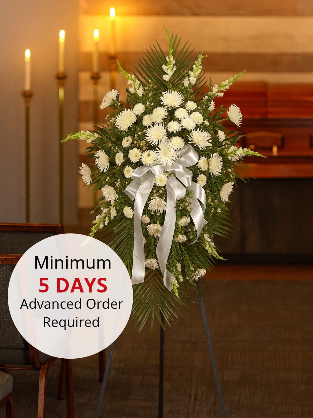 Tall white chrysanthemum standing spray with silver bow on an easel in a chapel setting
