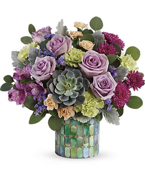 Compact arrangement of purple and peach flowers with a central succulent in a mosaic green cylinder vase