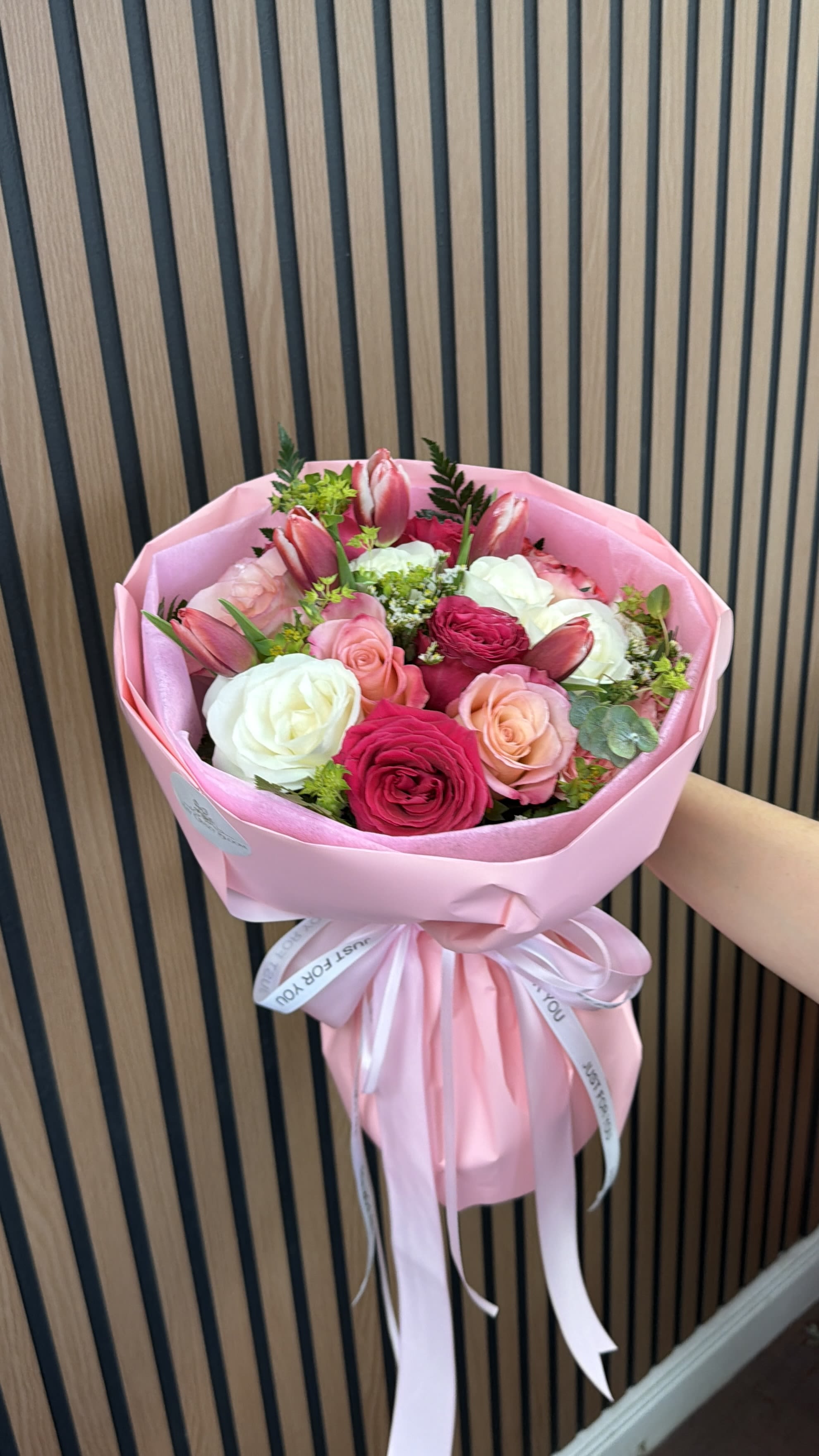 Pink bouquet of roses and tulips wrapped in pink paper