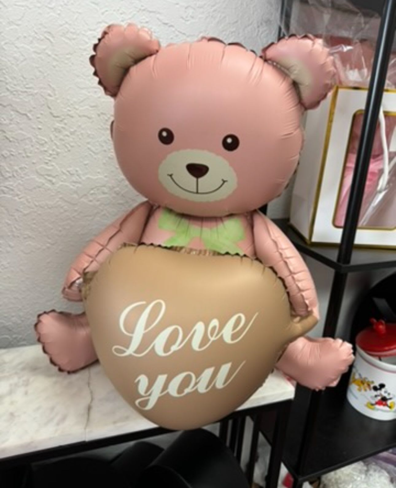 Pink teddy bear balloon holding a heart balloon that says "Love you"