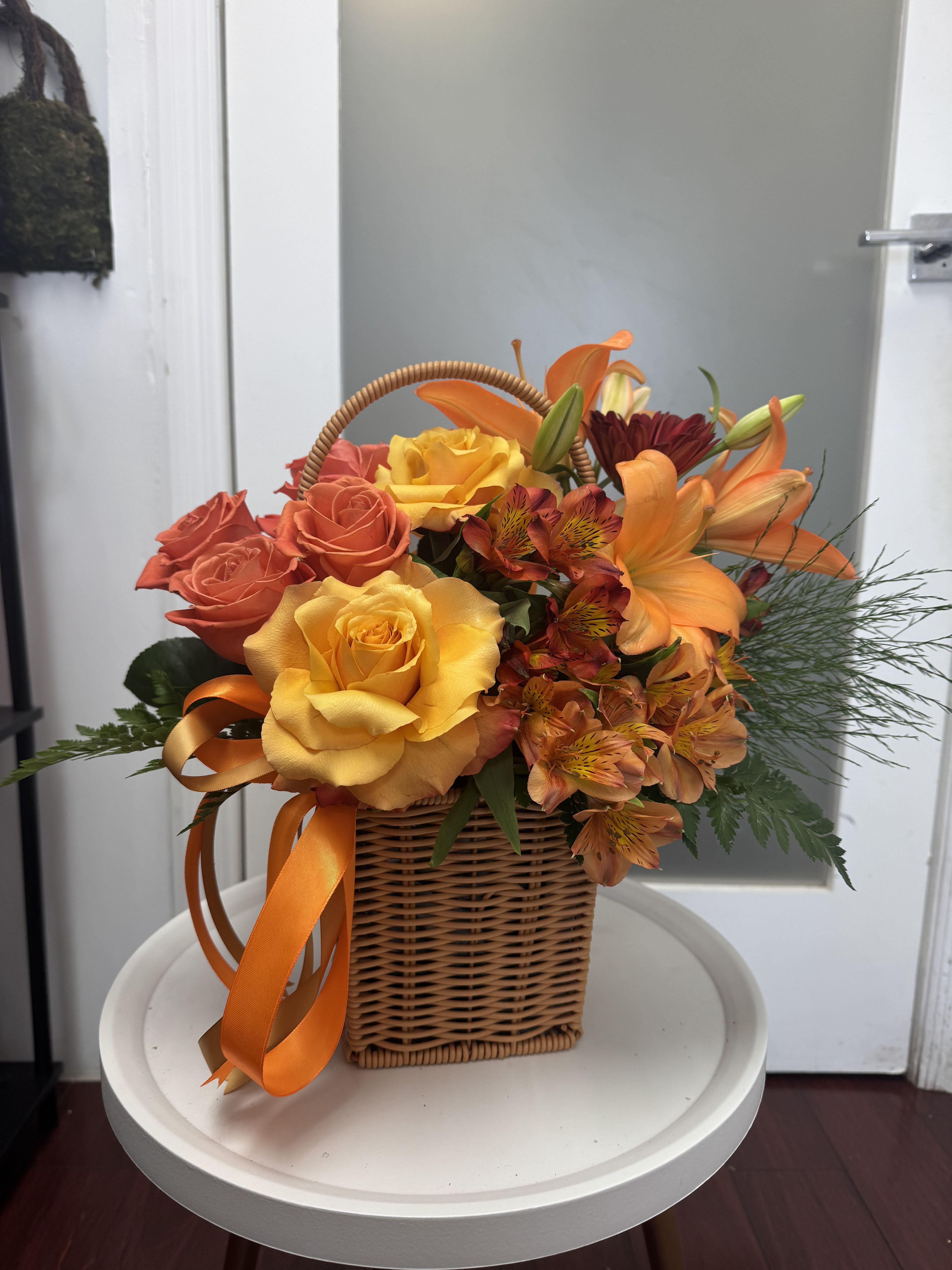 Basket of orange and yellow roses with lilies and ribbon