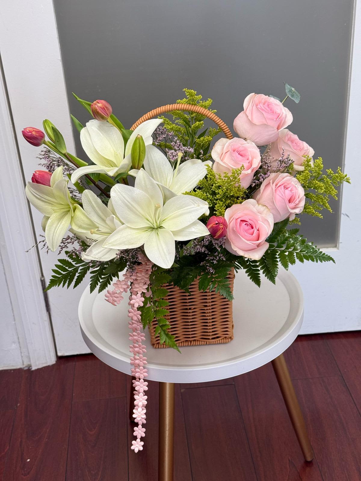 Basket arrangement of pink roses and white lilies