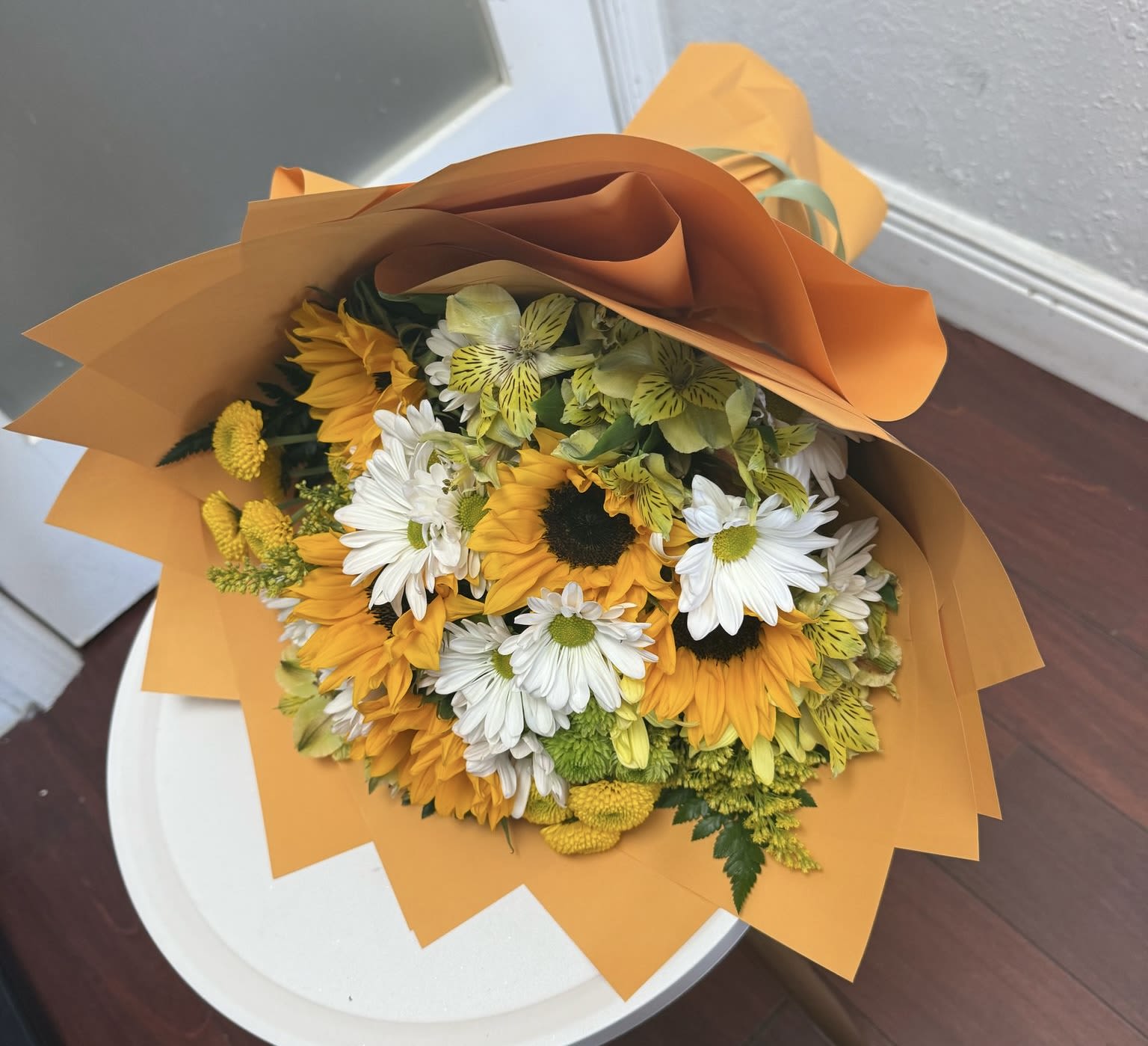 Bouquet of sunflowers and white daisies wrapped in orange paper