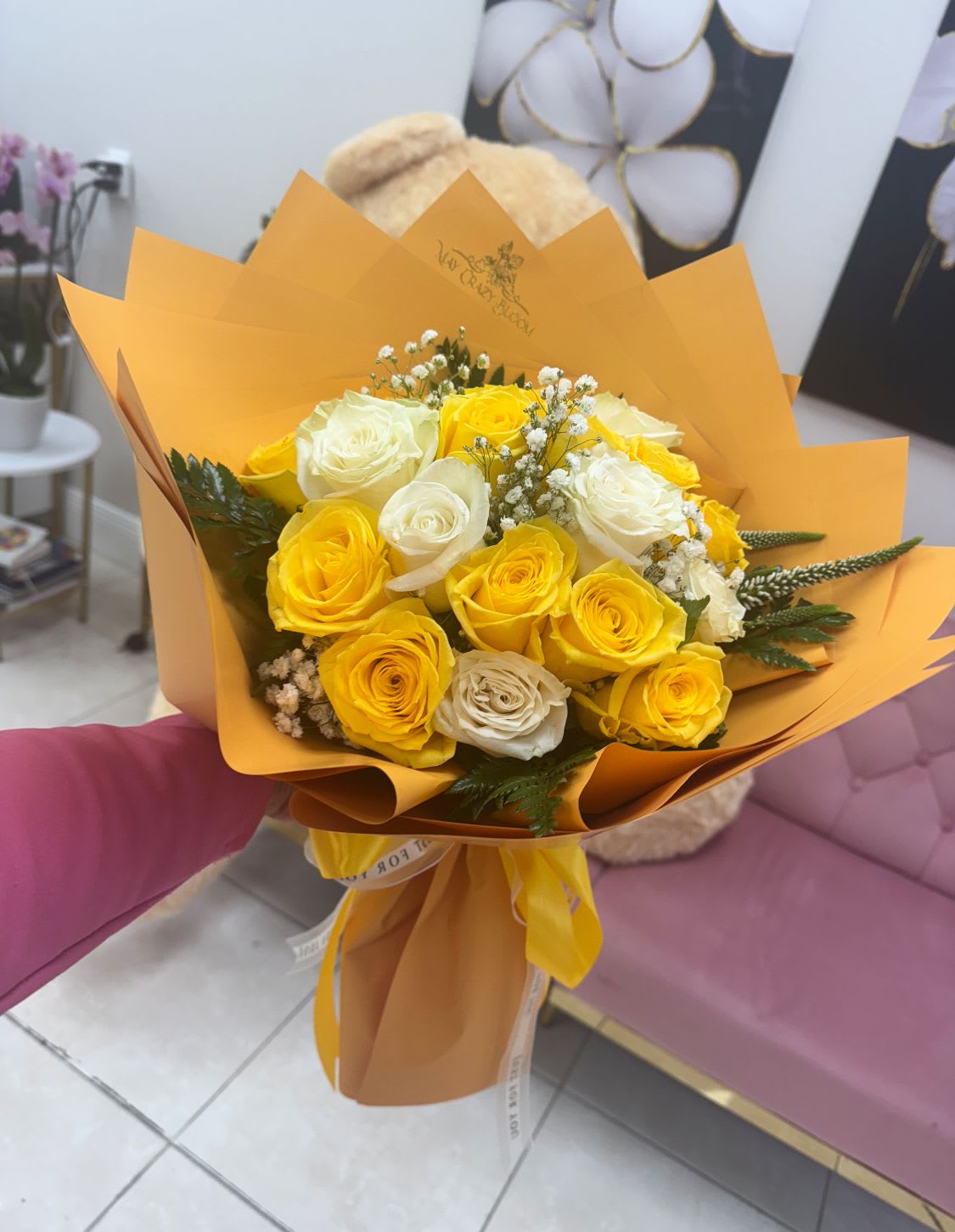 Bouquet of yellow and white roses wrapped in orange paper