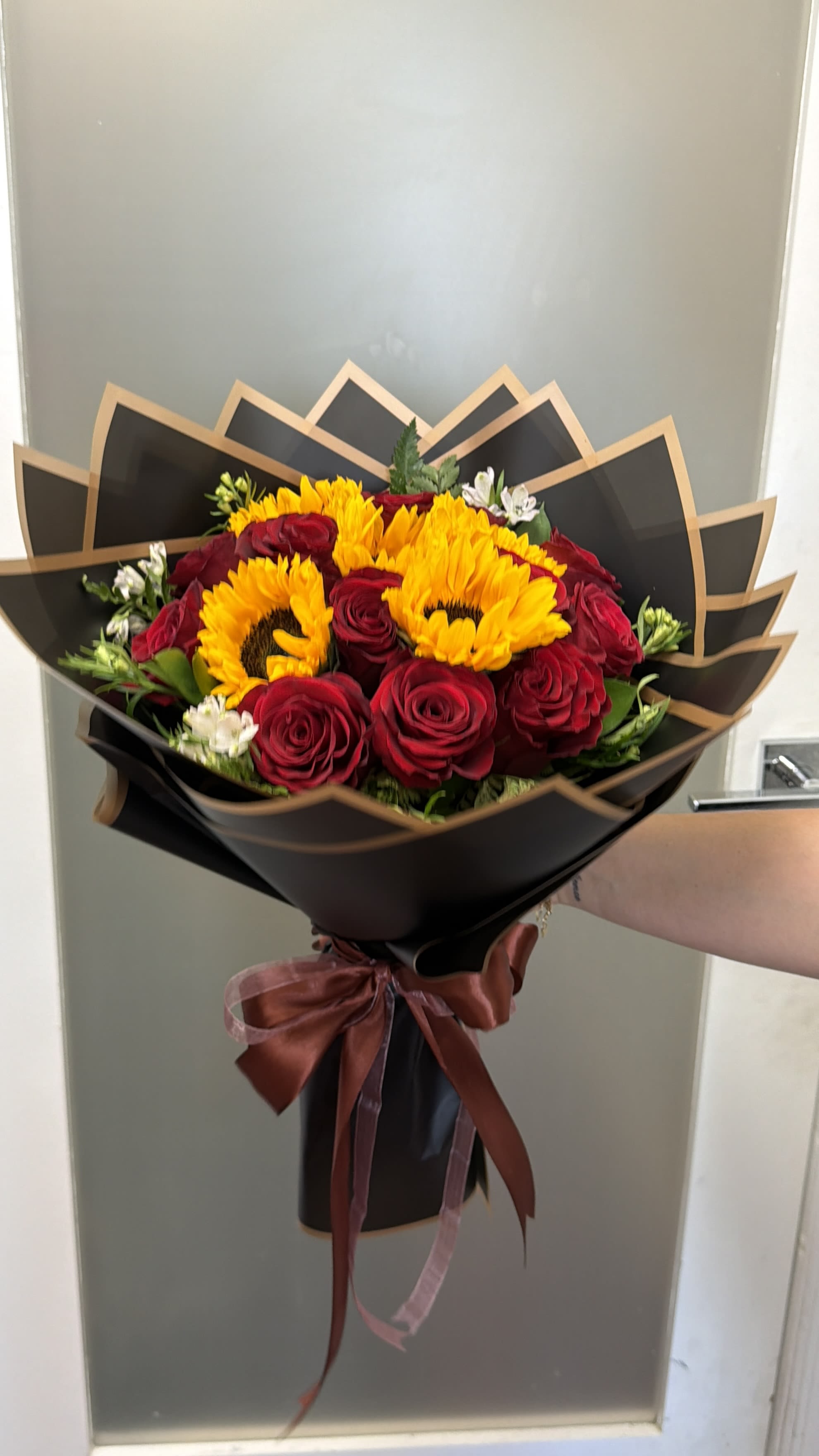 Bouquet of red roses and yellow sunflowers wrapped in black paper
